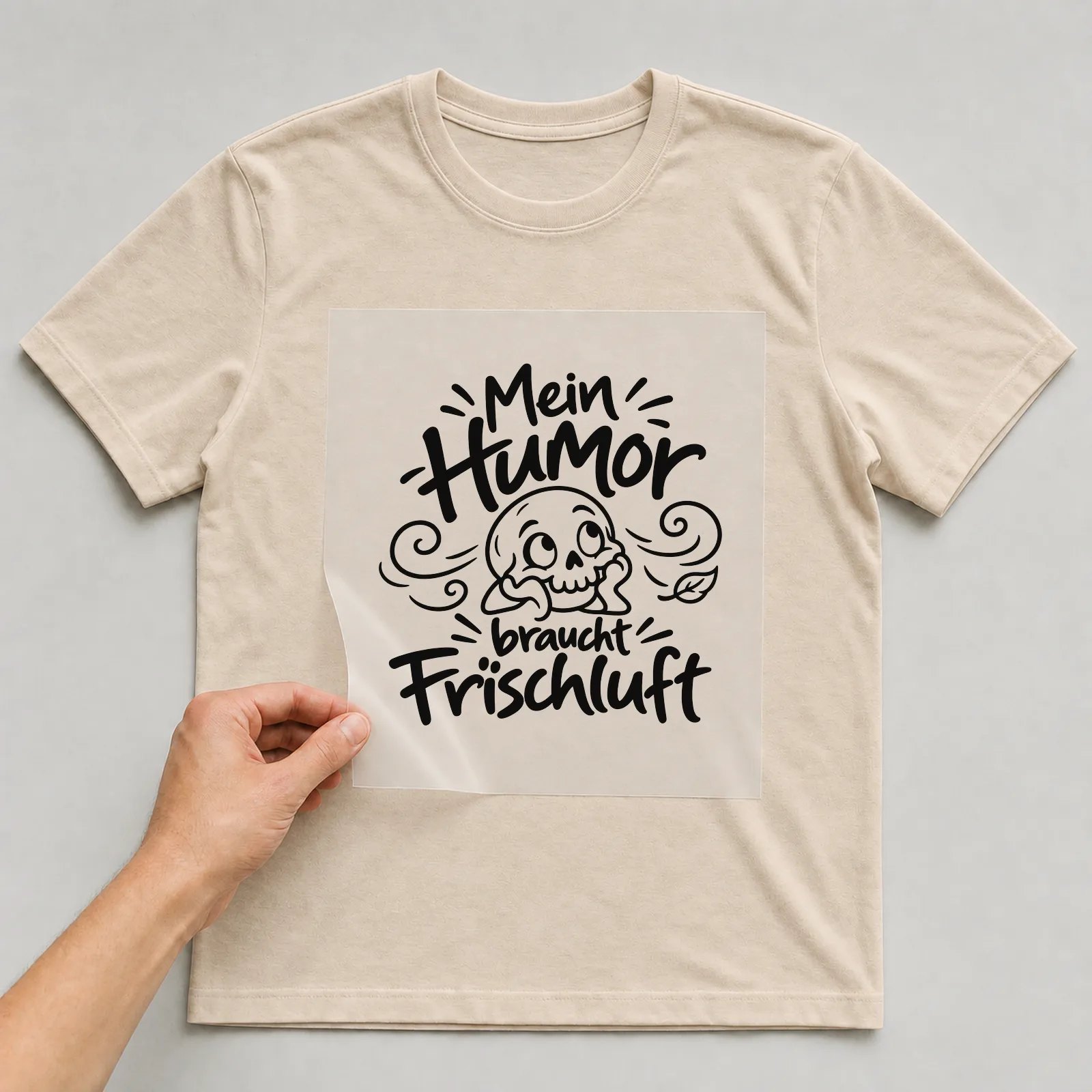Bügelbild „Mein Humor braucht Frischluft“ auf beigem T-Shirt, Folie wird aufgelegt