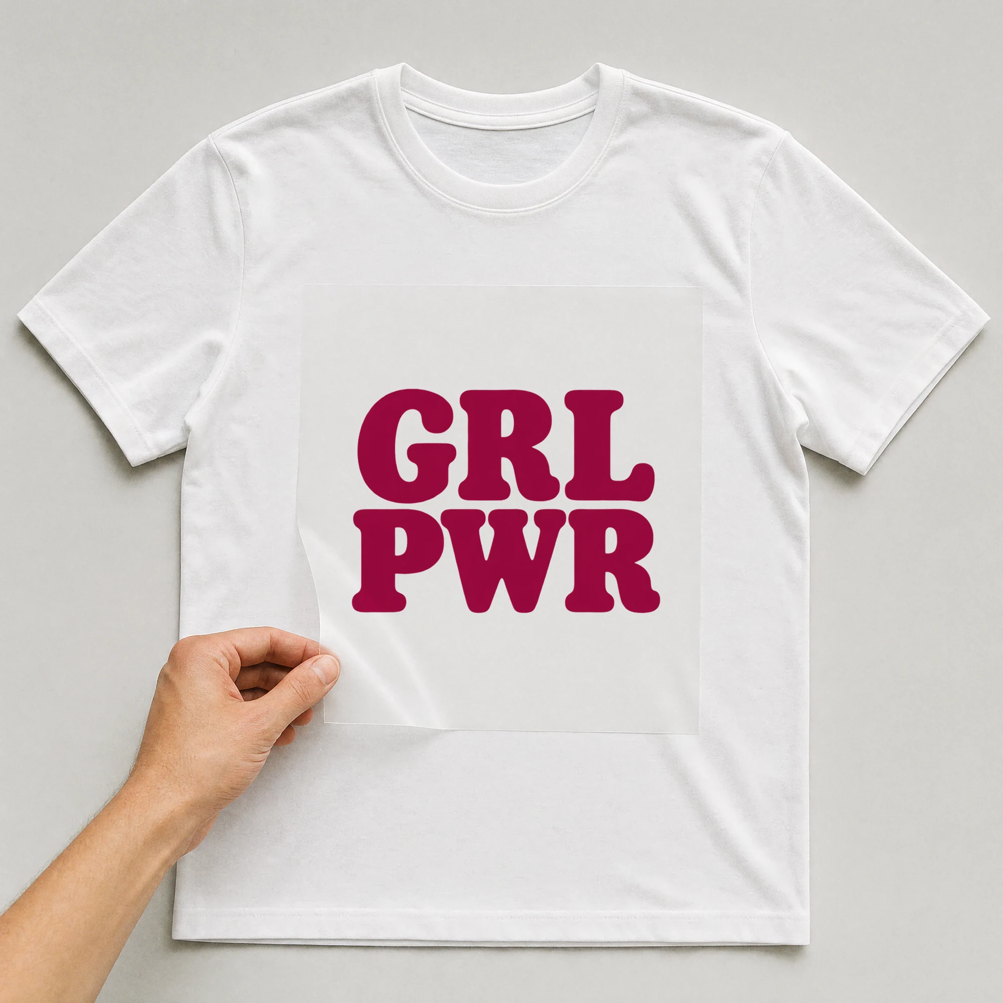 Bügelbild „GRL PWR“ auf weißem T-Shirt, Folie wird aufgelegt