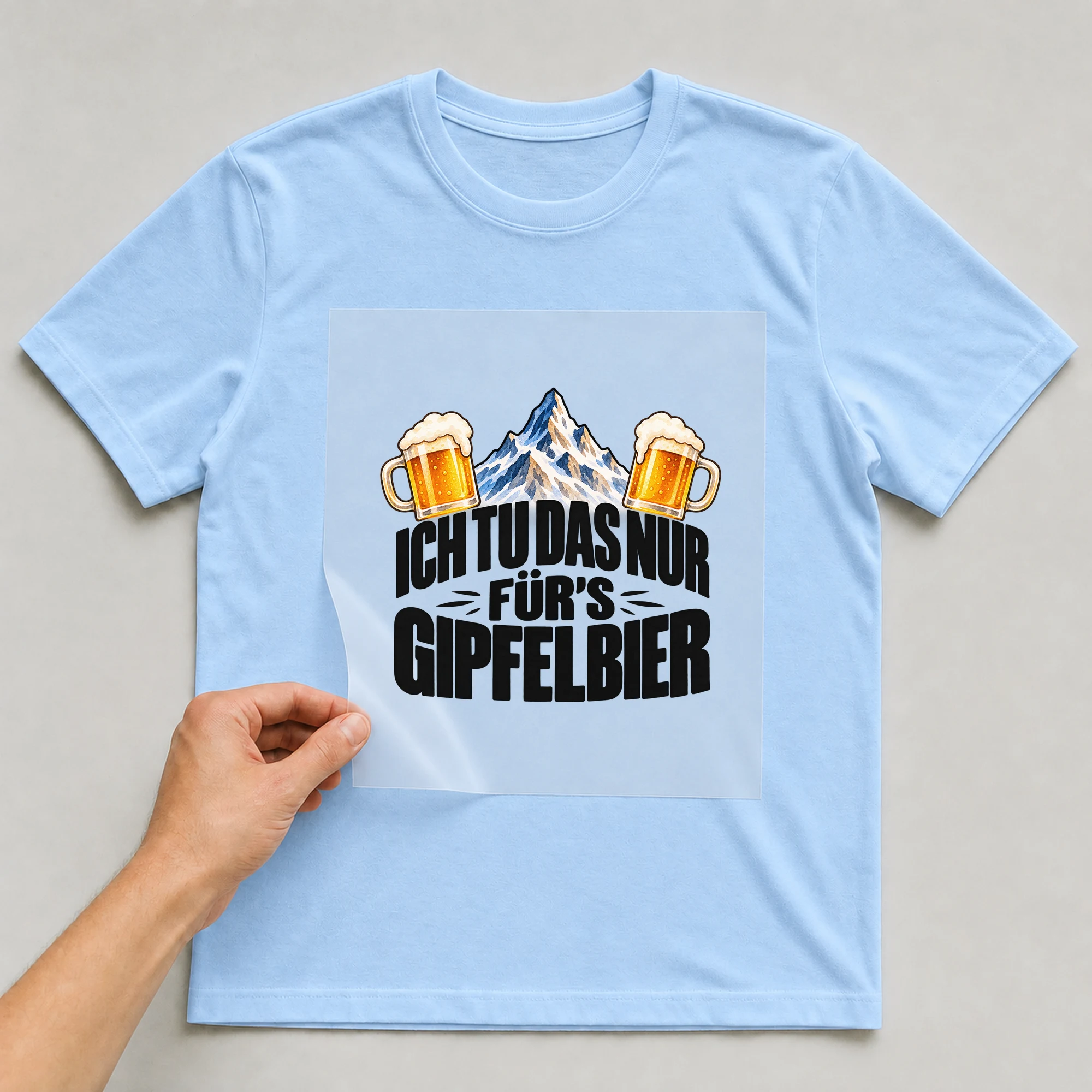 Bügelbild „Ich tu das nur für's Gipfelbier“ auf babyblauem T-Shirt, Folie wird aufgelegt