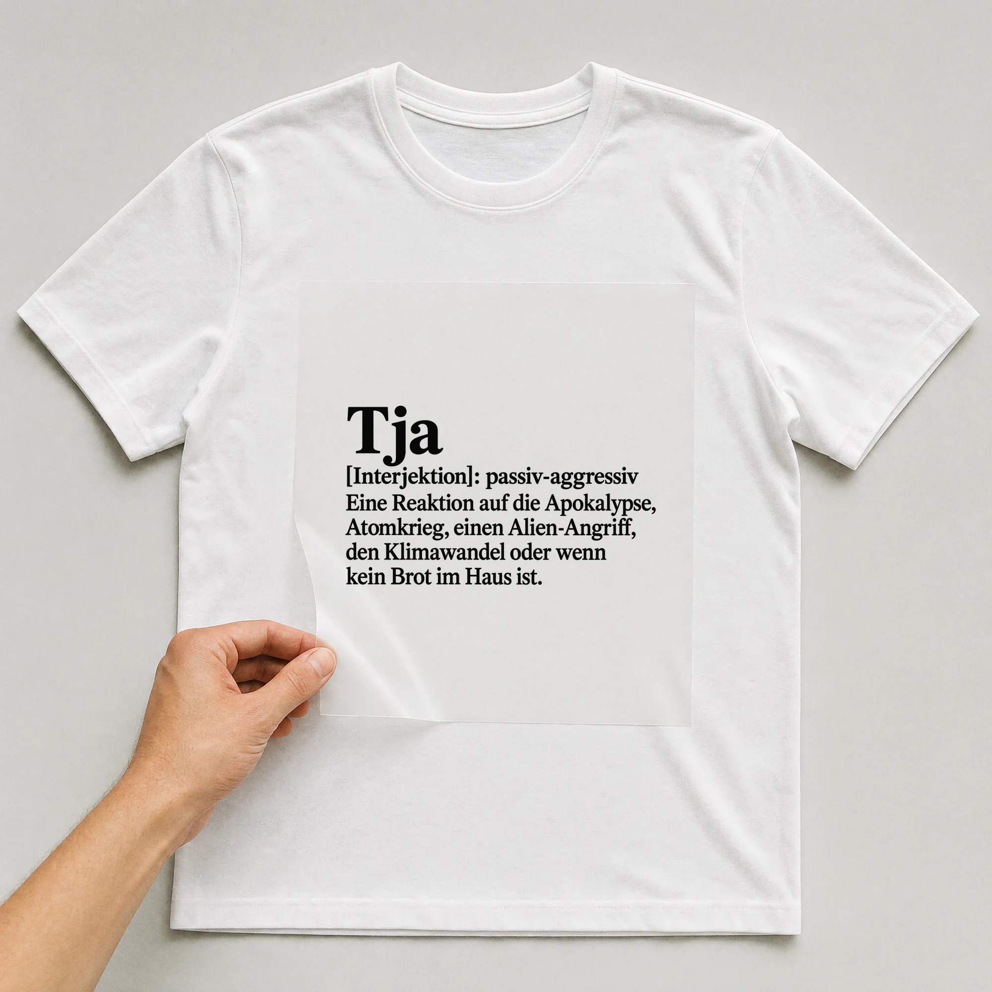Bügelbild „Tja [Interjektion]: Passiv-aggressiv eine Reaktion auf die Apokalypse“ auf weißem T-Shirt, Folie wird aufgelegt