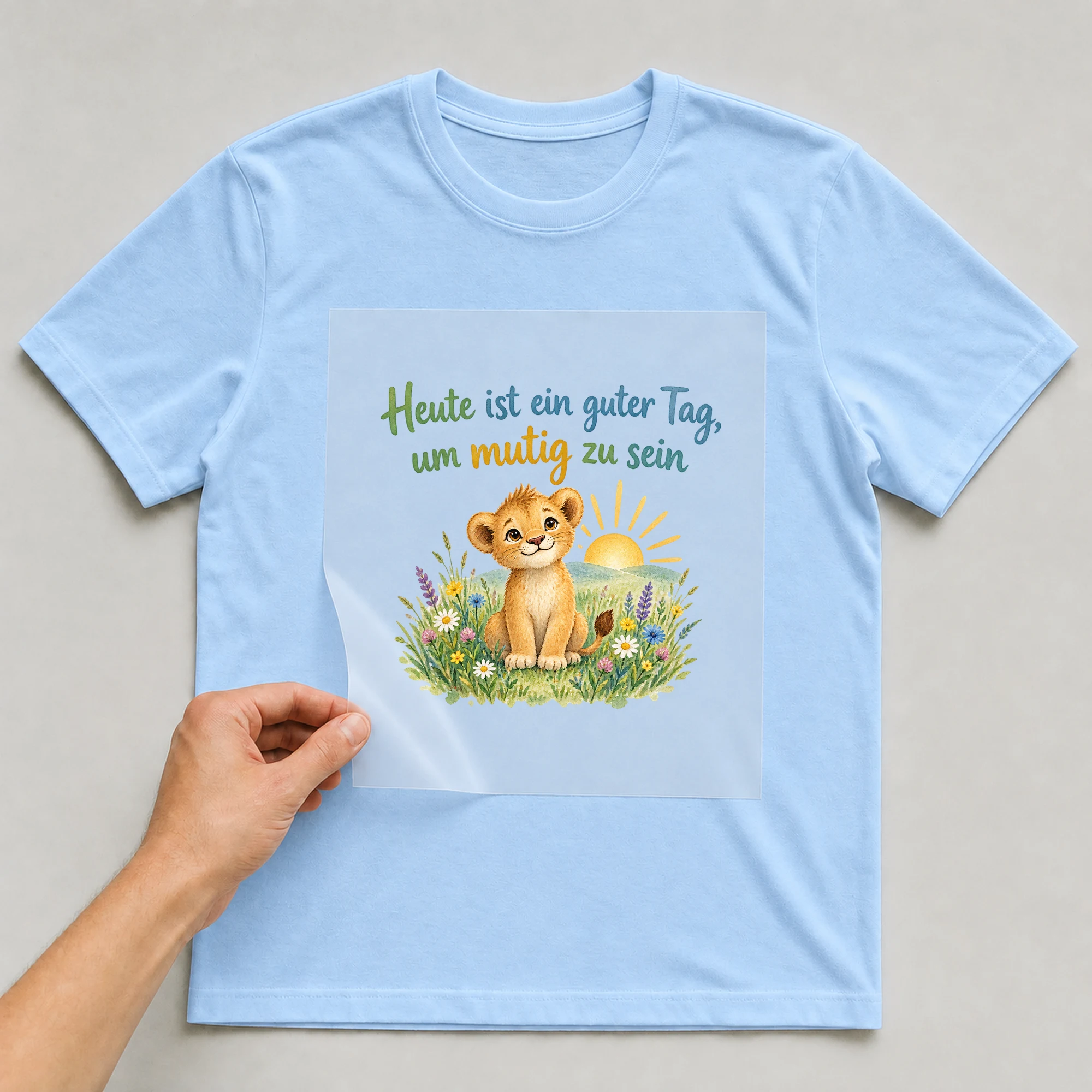 Bügelbild „Heute ist ein guter Tag, um mutig zu sein“ auf babyblauem T-Shirt, Folie wird aufgelegt
