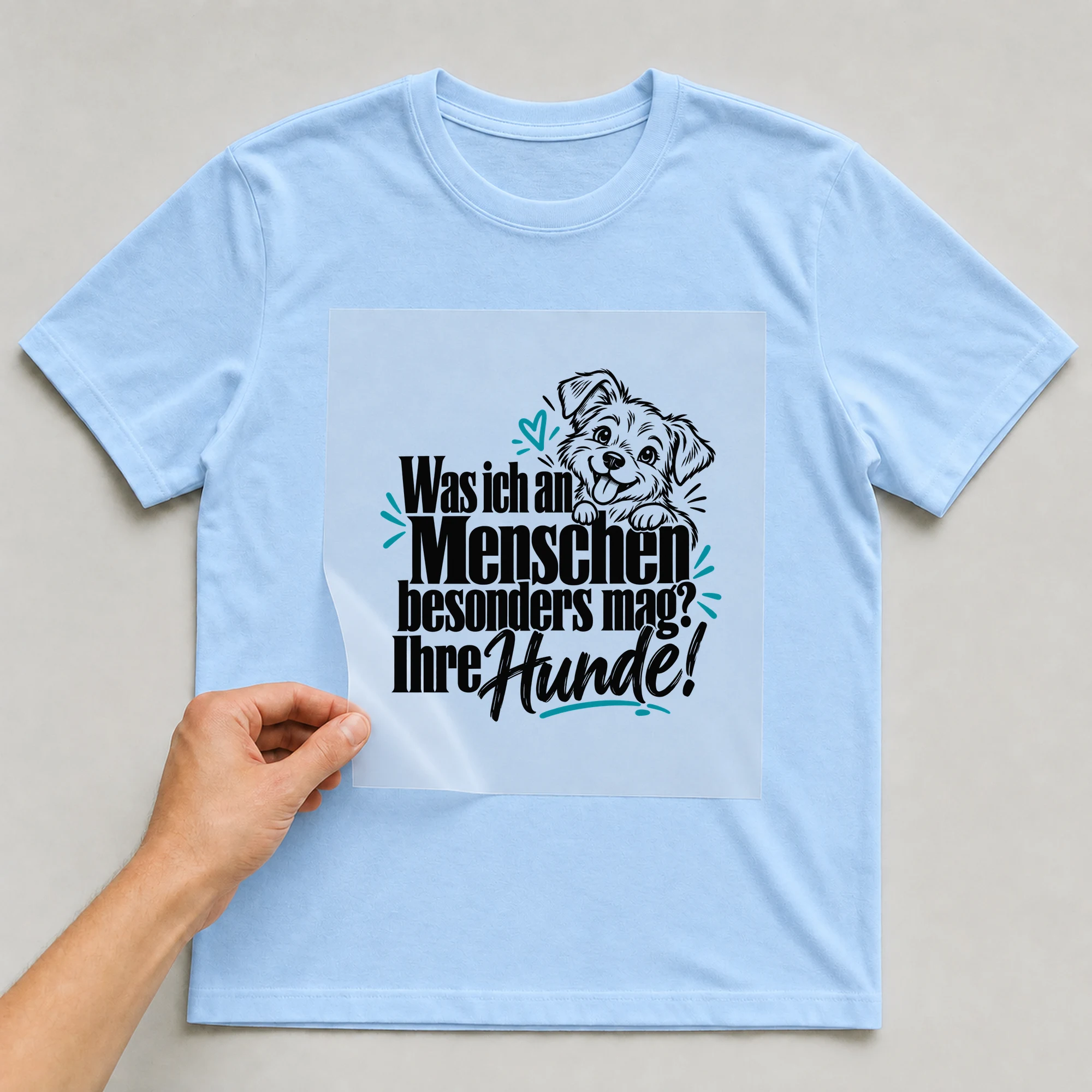 Bügelbild „Was ich an Menschen besonders mag? Ihre Hunde!“ auf babyblauem T-Shirt, Folie wird aufgelegt