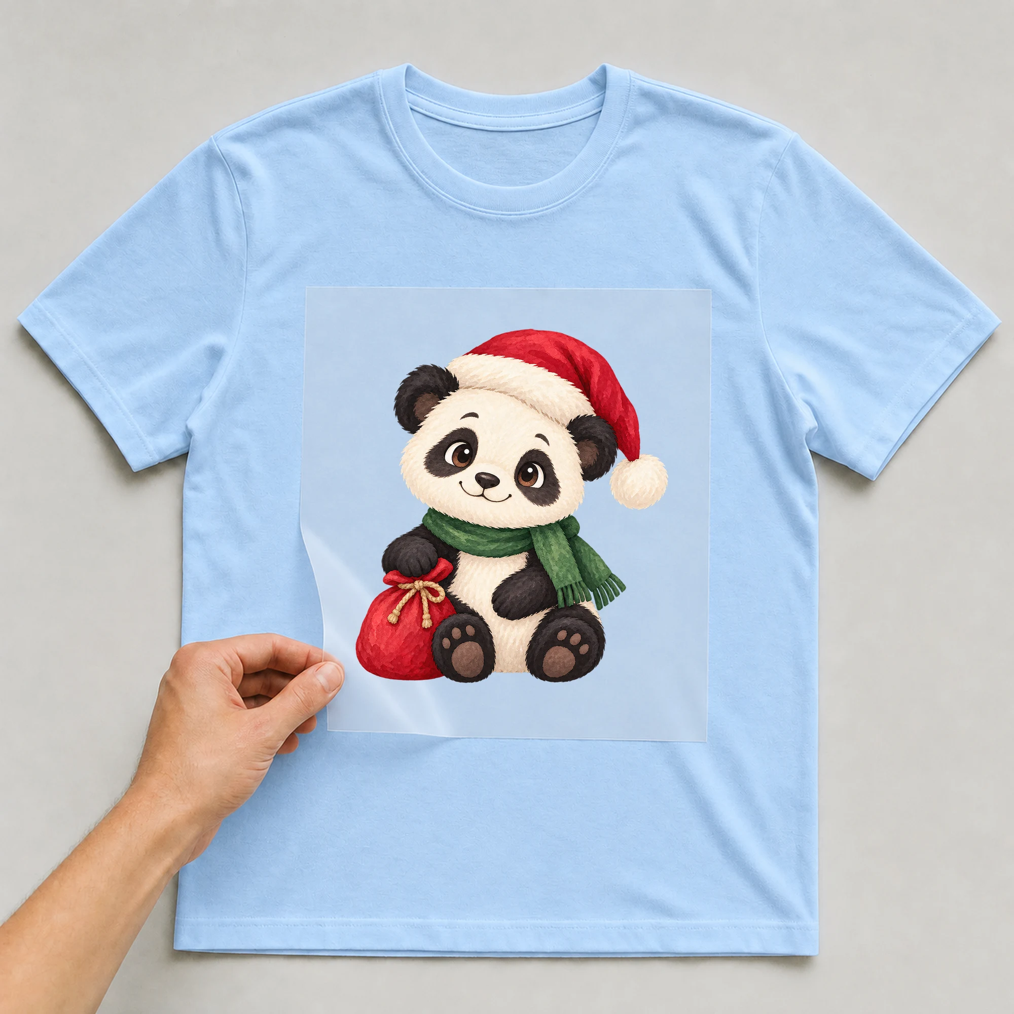 Bügelbild „Weihnachtsbär“ auf babyblauem T-Shirt, Folie wird aufgelegt