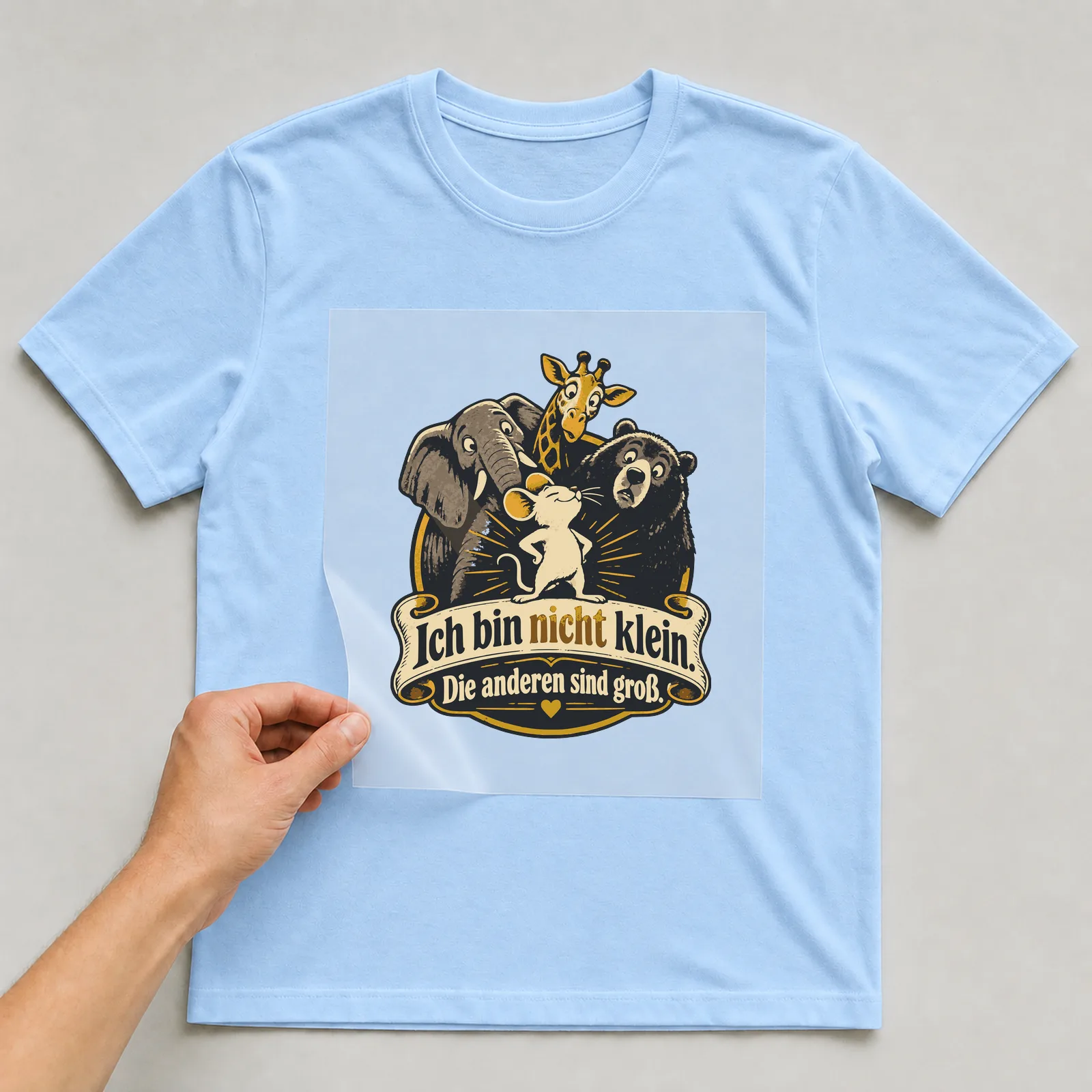 Bügelbild Ich bin nicht klein. Die anderen sind groß. auf hellblauem T-Shirt, Folie wird aufgelegt