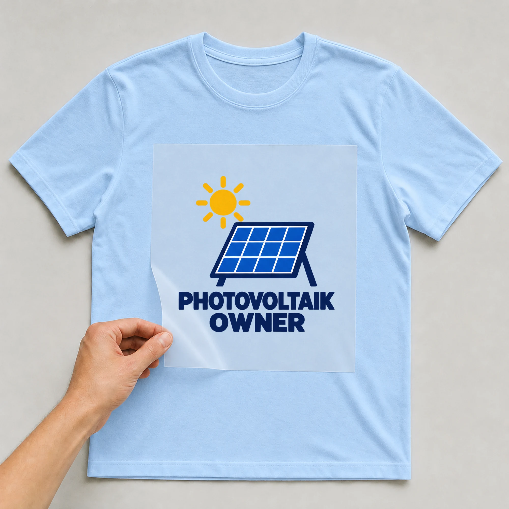 Bügelbild „PHOTOVOLTAIK OWNER“ auf babyblauem T-Shirt, Folie wird aufgelegt