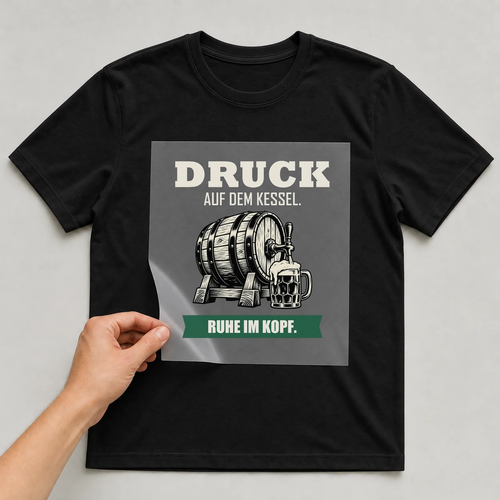 Bügelbild „Druck auf dem kessel. Ruhe im Kopf.“ auf schwarzem T-Shirt, Folie wird aufgelegt