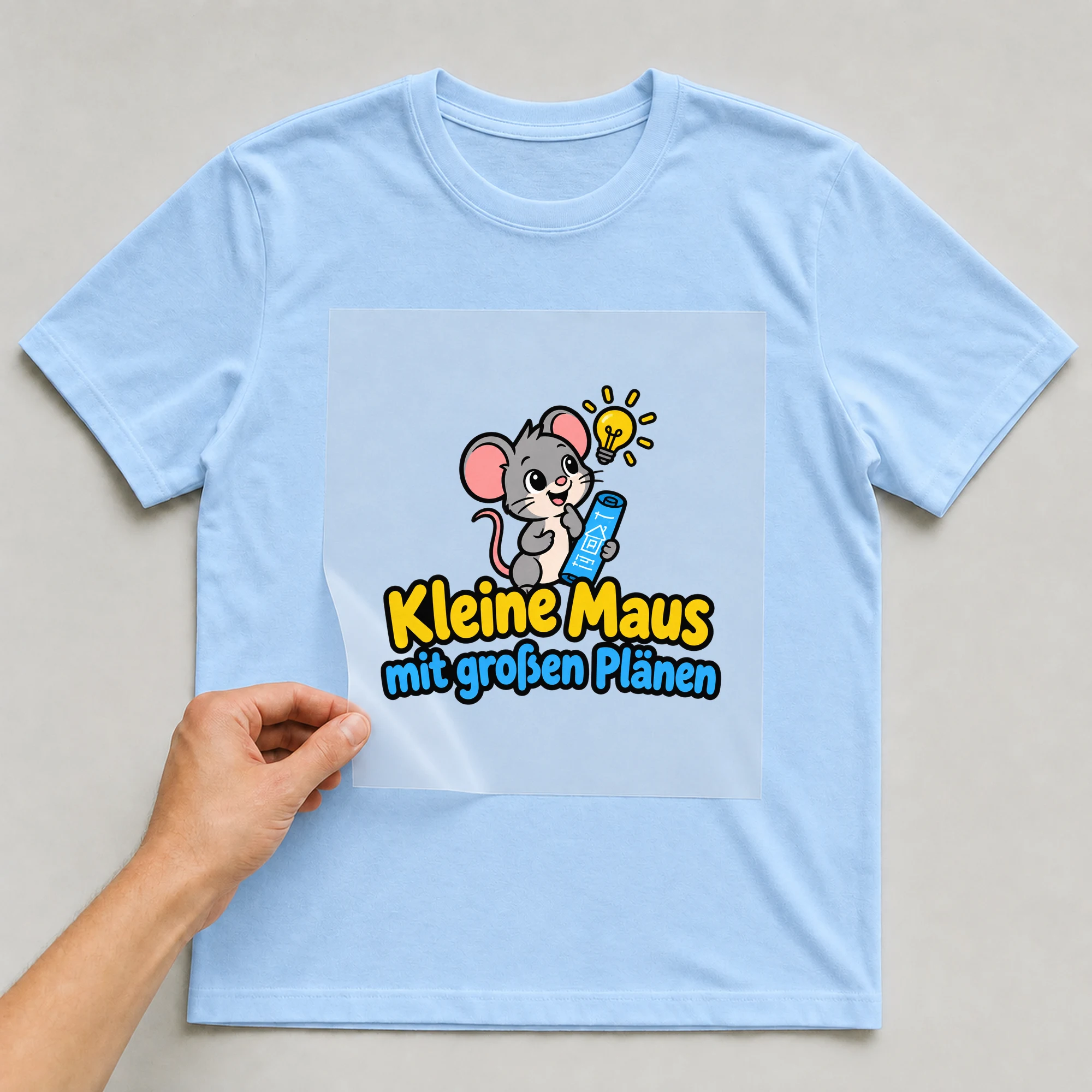 Bügelbild „Kleine Maus mit großen Plänen“ auf babyblauem T-Shirt, Folie wird aufgelegt