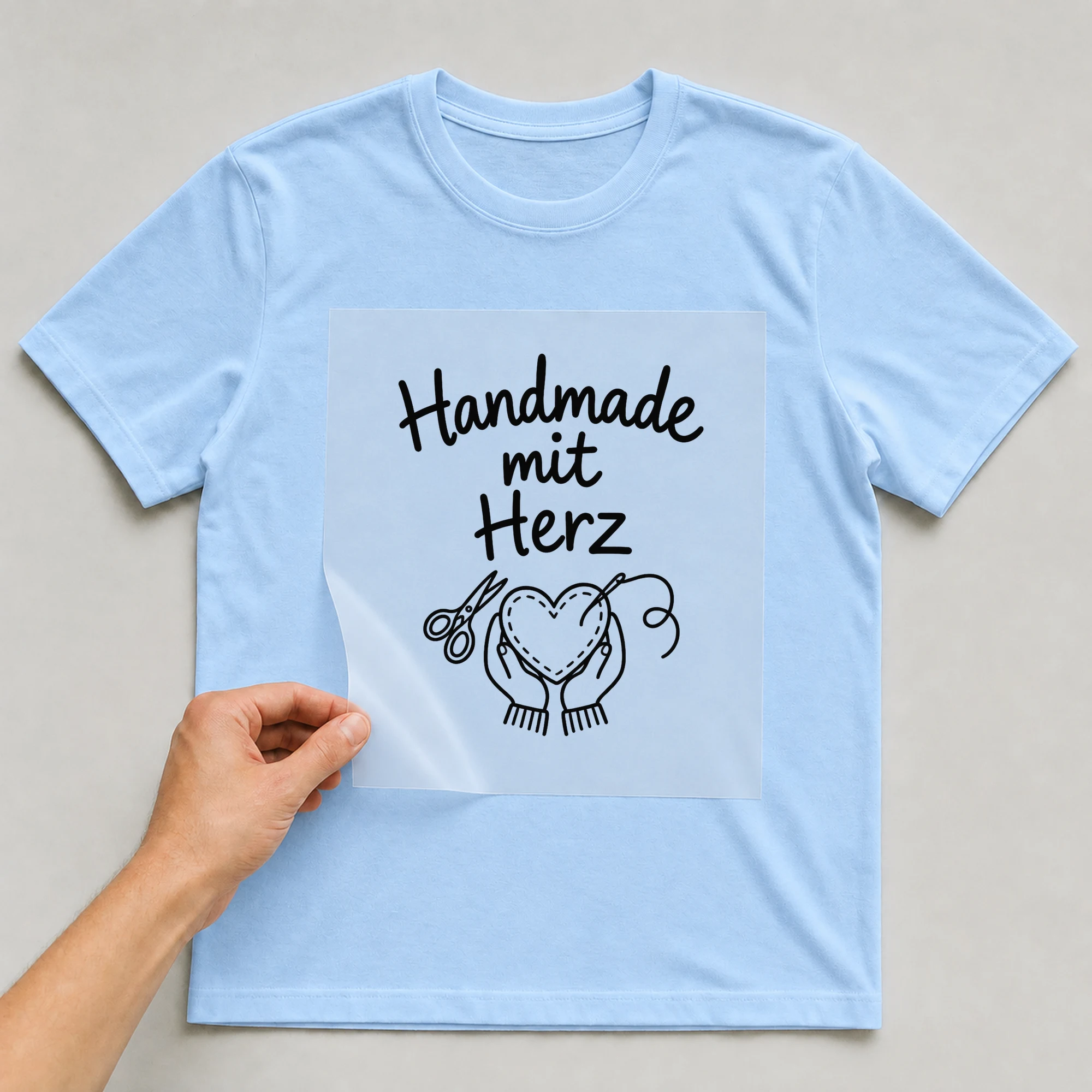 Bügelbild „Handmade mit Herz“ auf babyblauem T-Shirt, Folie wird aufgelegt