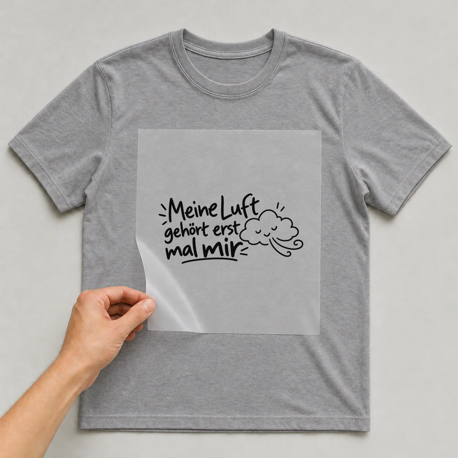 Bügelbild „Meine Luft gehört erst mal mir“ auf grauem T-Shirt, Folie wird aufgelegt