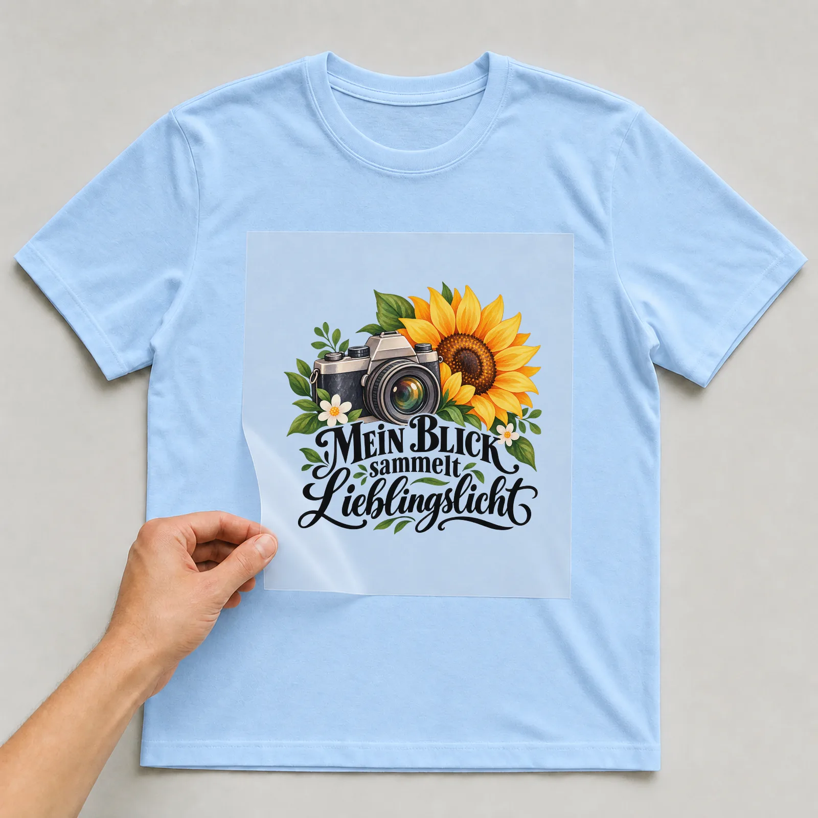 Bügelbild „MEIN BLICK sammelt Lieblingslicht“ auf hellblauem T-Shirt, Folie wird aufgelegt