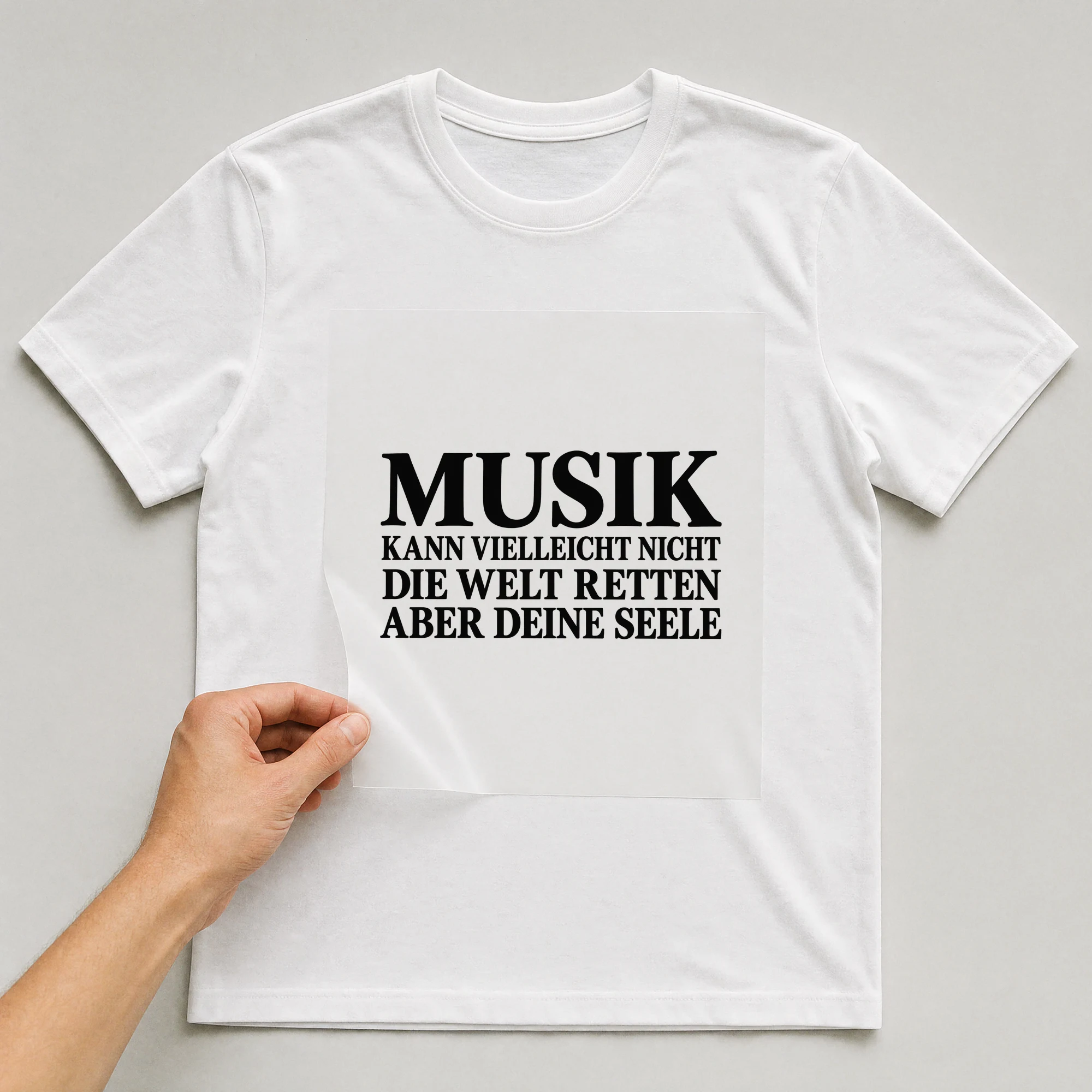 Bügelbild „Musik kann vielleicht nicht die Welt retten aber deine Seele“ auf weißem T-Shirt, Folie wird aufgelegt