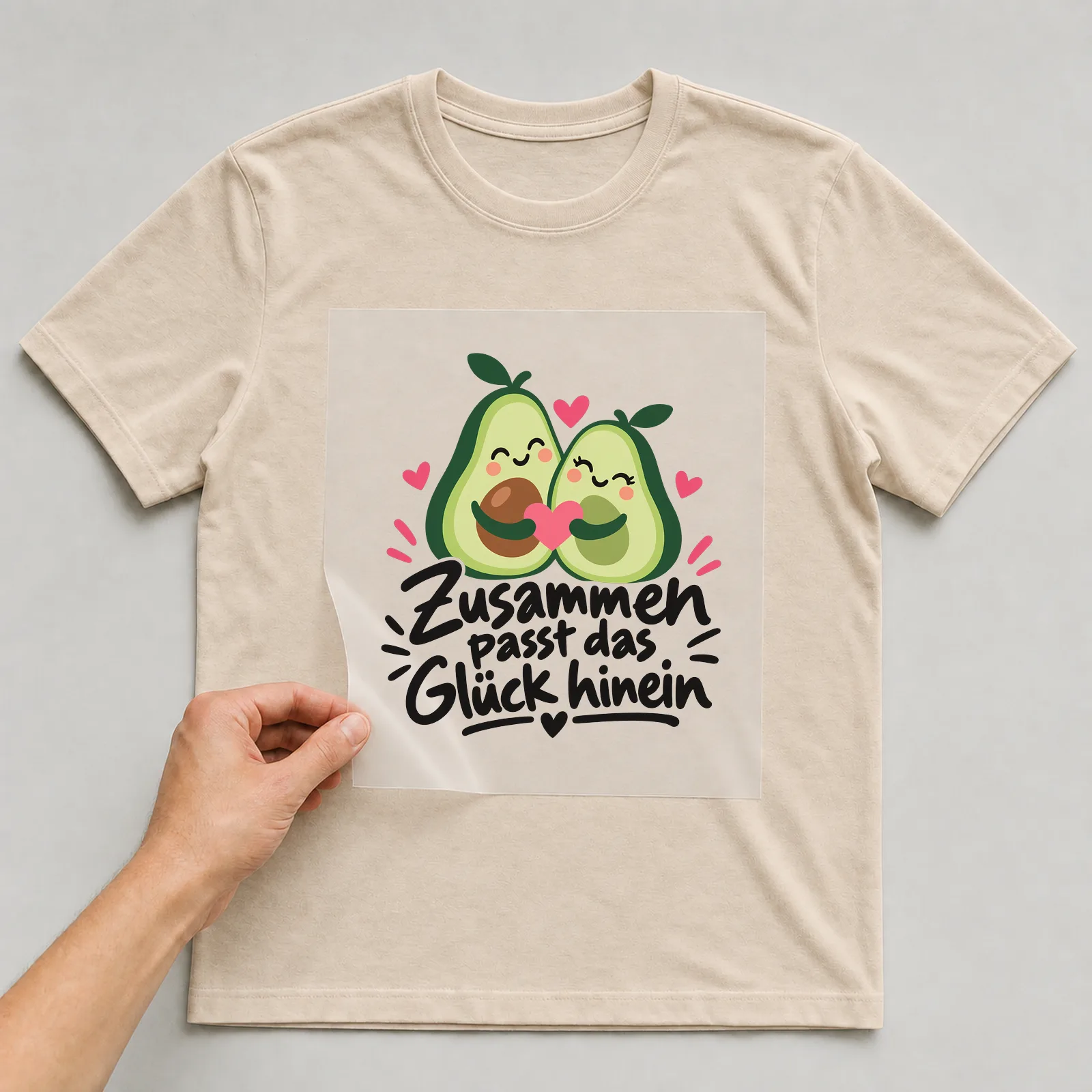 Bügelbild „Zusammen passt das Glück hinein“ auf beigem T-Shirt, Folie wird aufgelegt