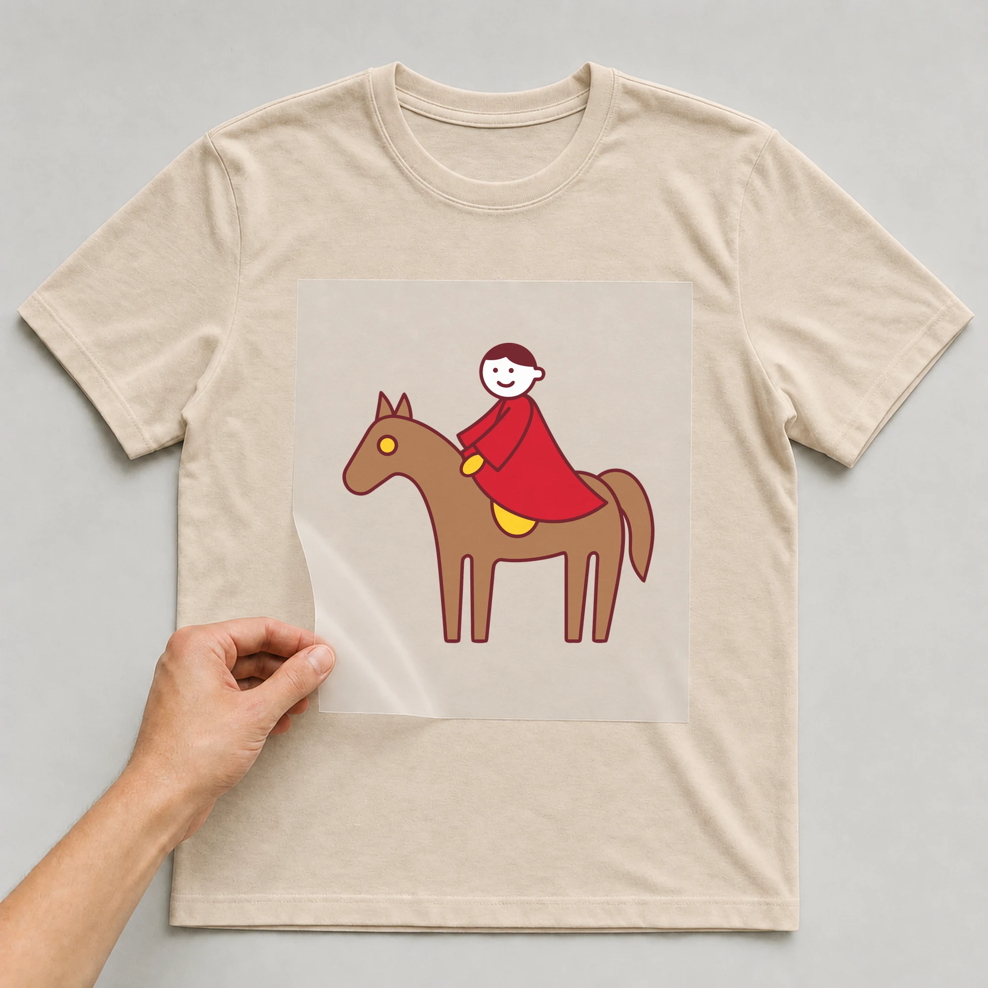 Bügelbild „Martinspferd mit Reiter“ auf beigem T-Shirt, Folie wird aufgelegt