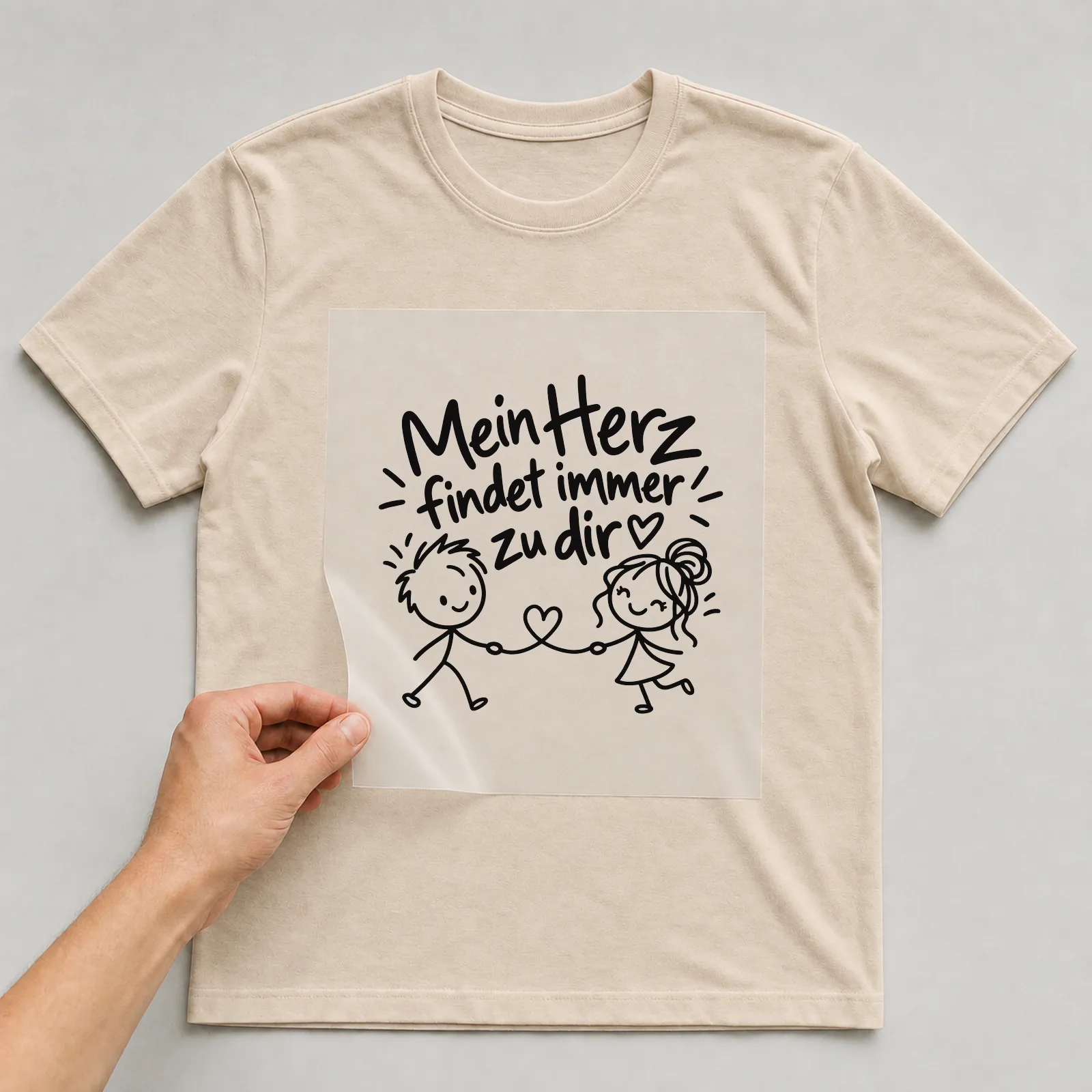 Bügelbild „Mein Herz findet immer zu dir“ auf beigem T-Shirt, Folie wird aufgelegt