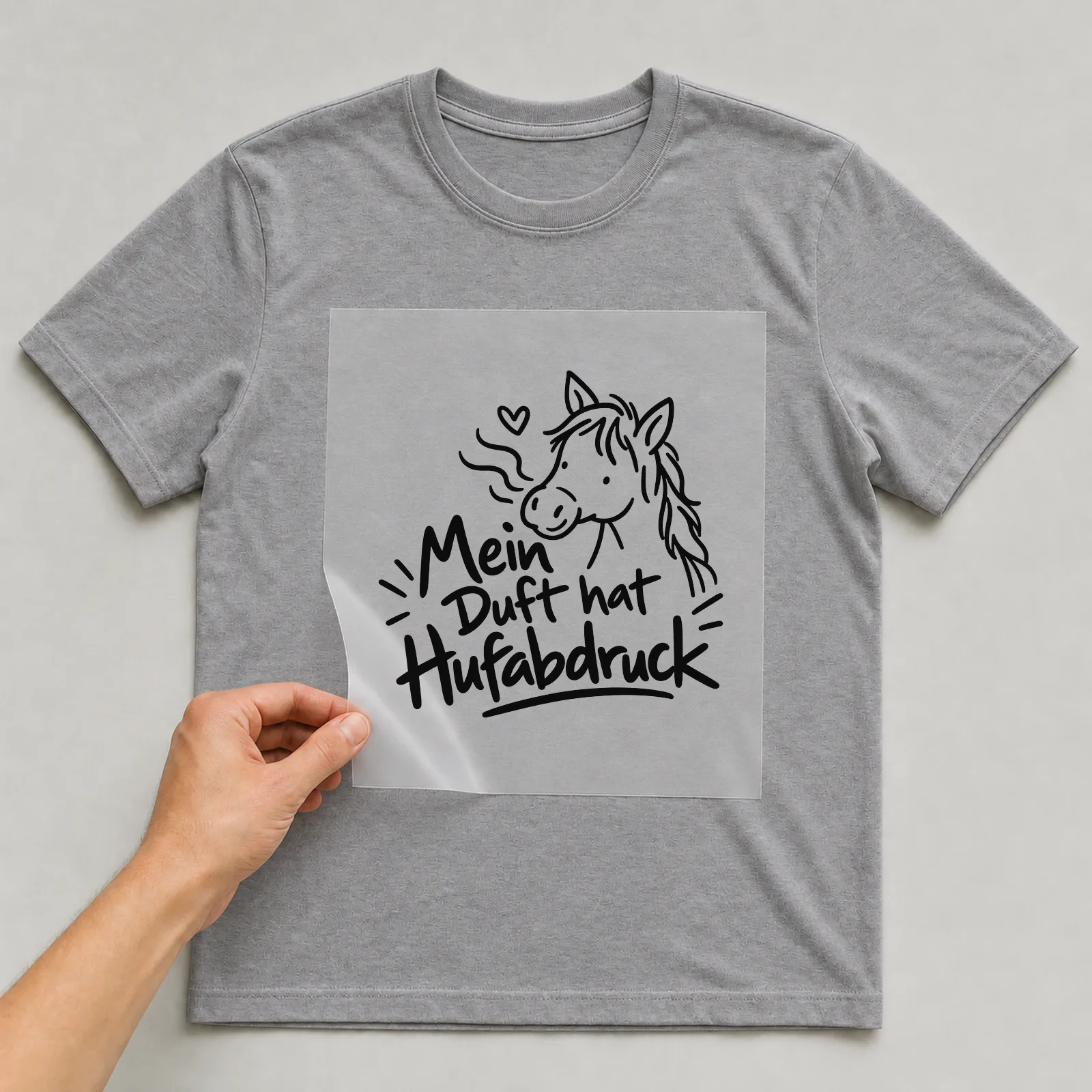 Bügelbild „Mein Duft hat Hufabdruck“ auf grauem T-Shirt, Folie wird aufgelegt