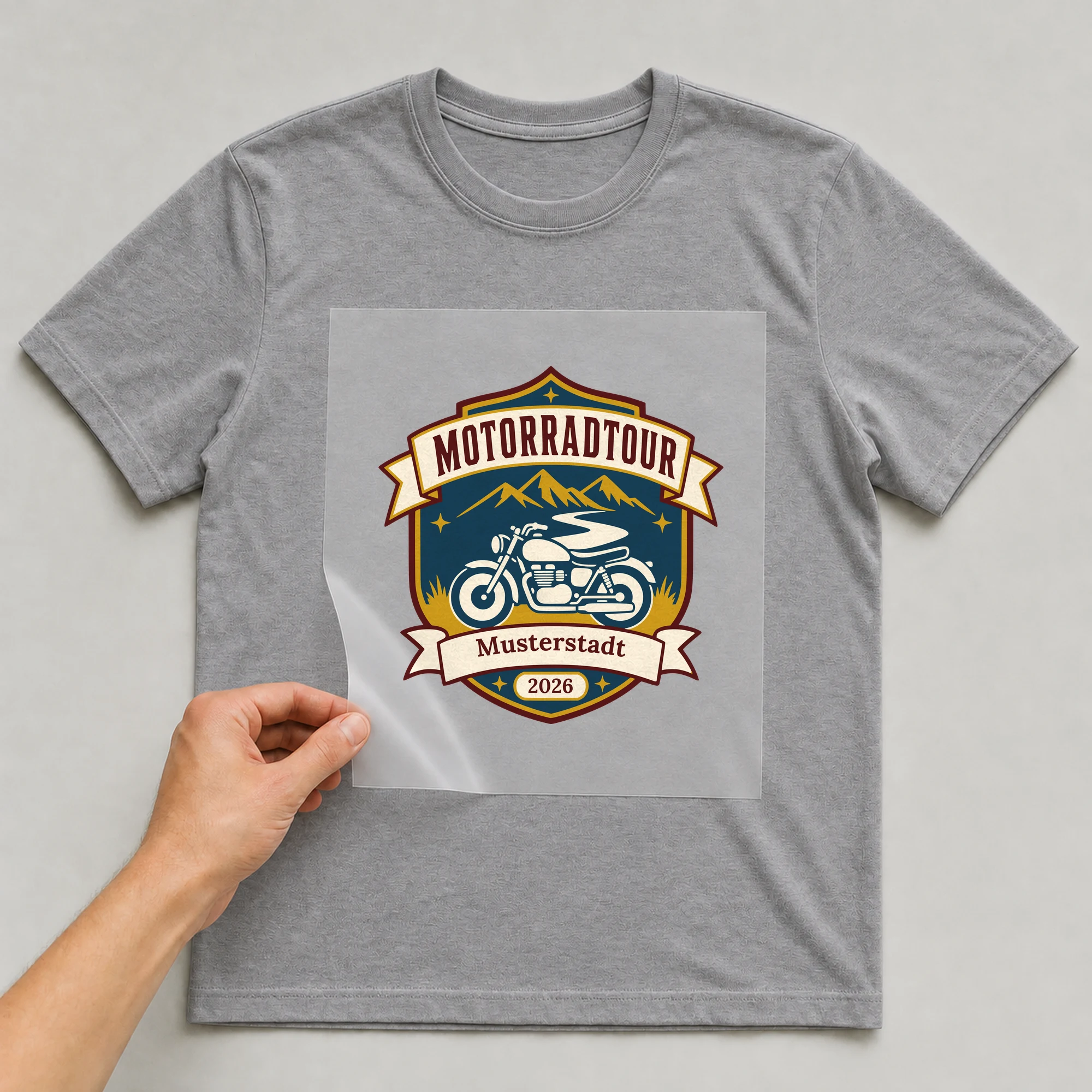 Bügelbild Motorradtour mit Ort und Jahr auf grauem T-Shirt, Folie wird aufgelegt