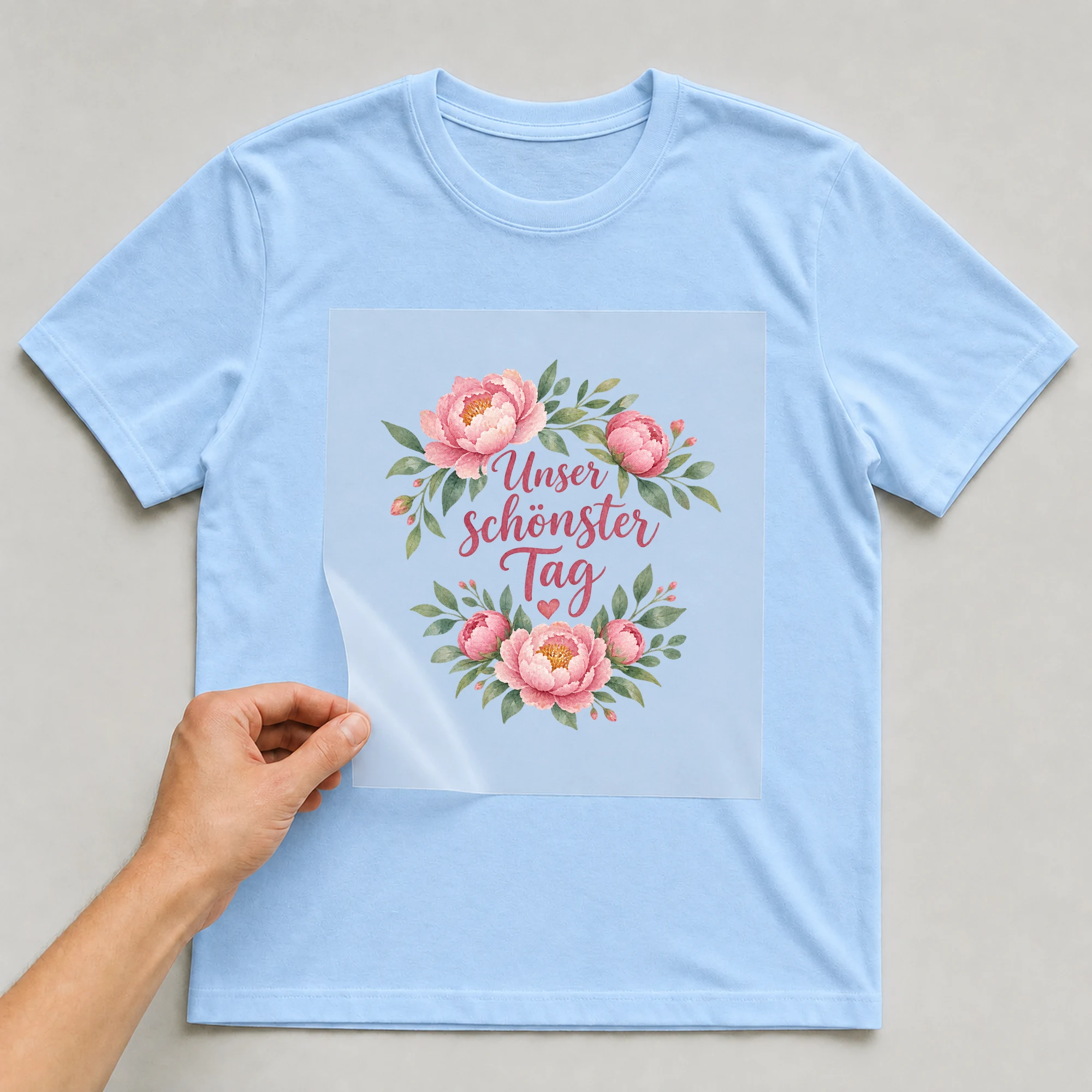 Bügelbild „Unser schönster Tag“ auf babyblauem T-Shirt, Folie wird aufgelegt