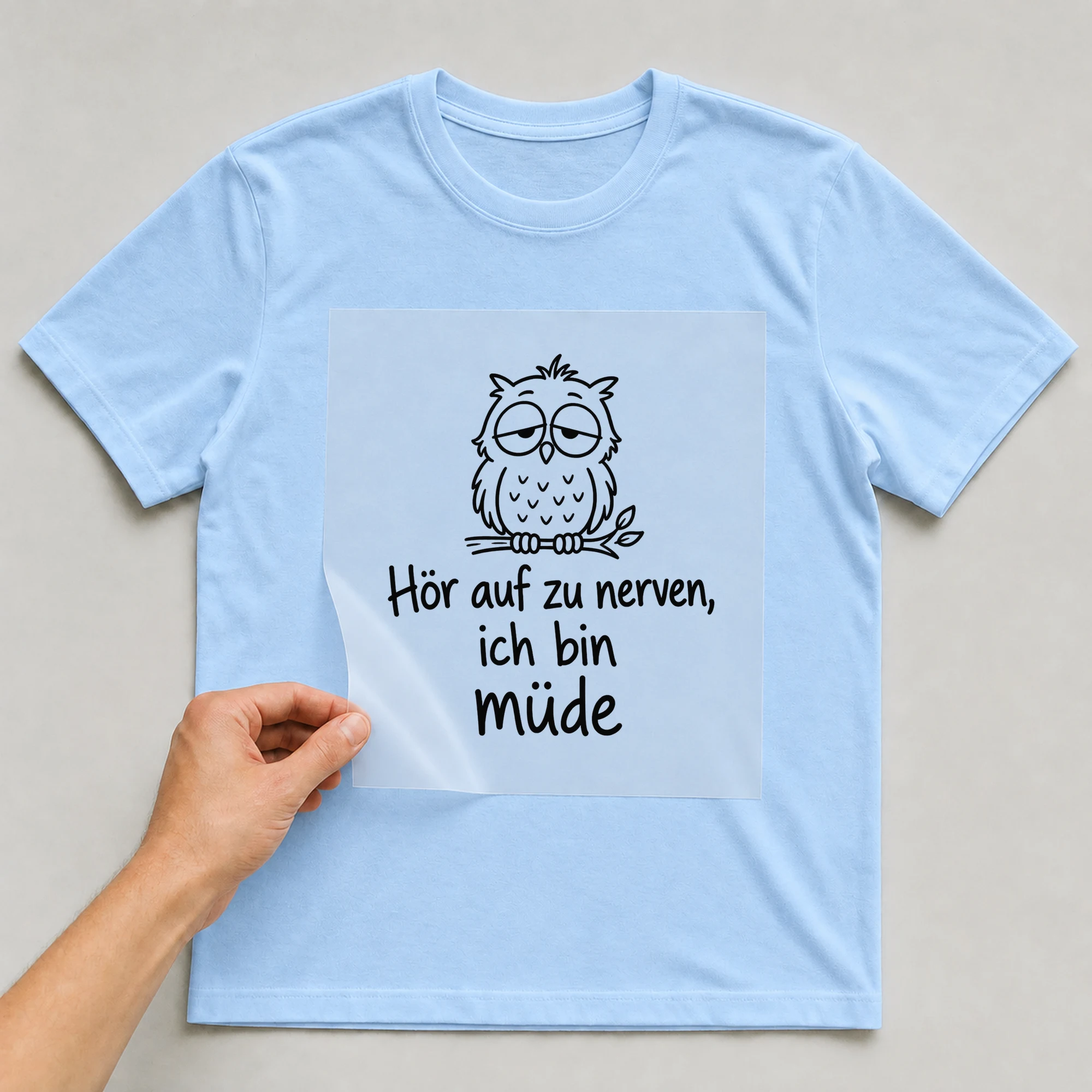 Bügelbild „Hör auf zu nerven, ich bin müde“ auf babyblauem T-Shirt, Folie wird aufgelegt