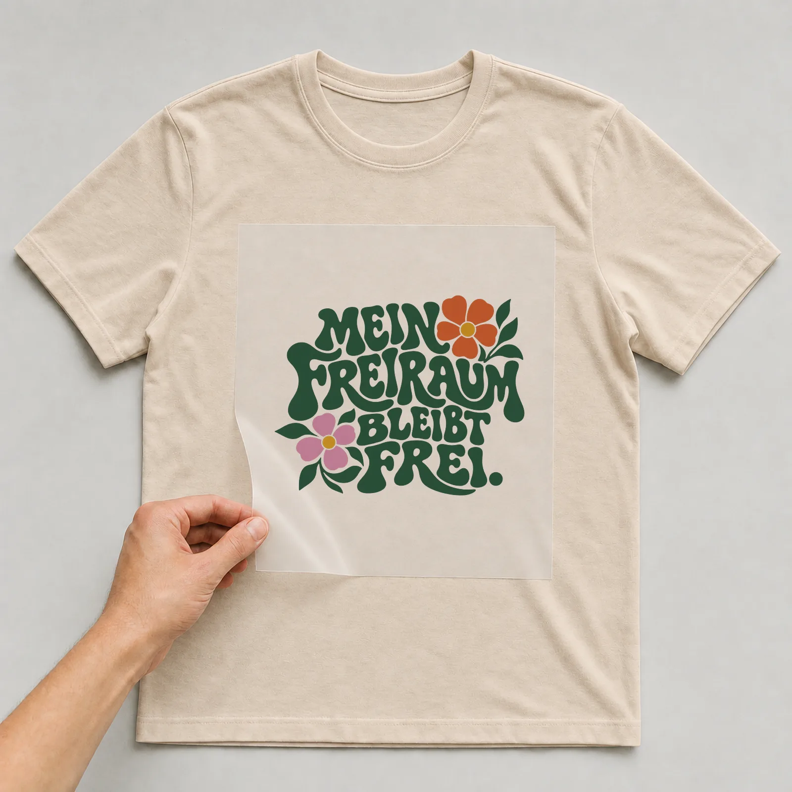 Bügelbild „Mein Freiraum bleibt frei“ auf beigem T-Shirt, Folie wird aufgelegt