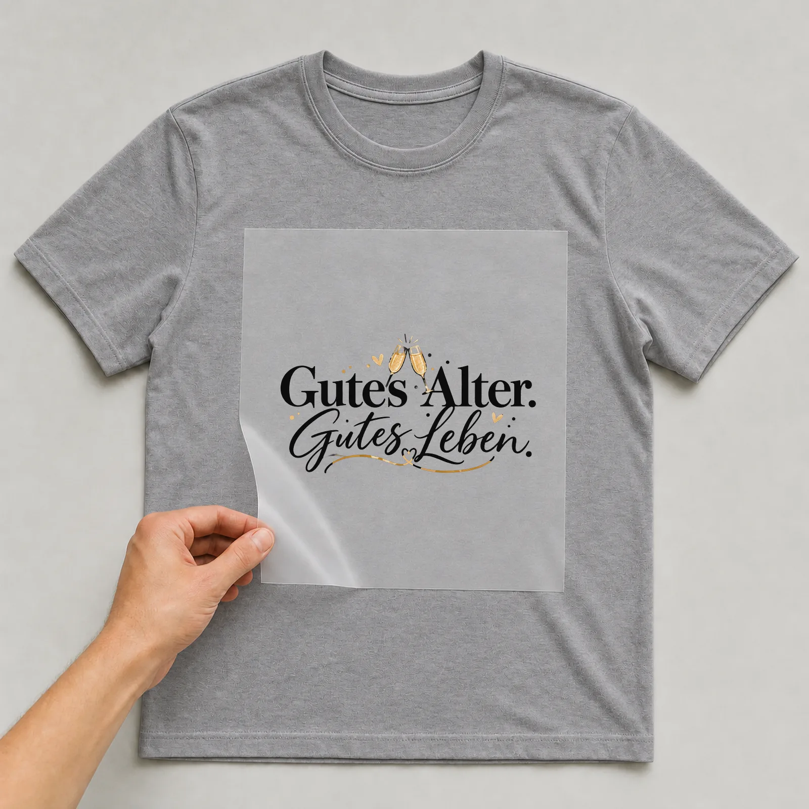 Bügelbild „Gutes Alter. Gutes Leben.“ auf grauem T-Shirt, Folie wird aufgelegt