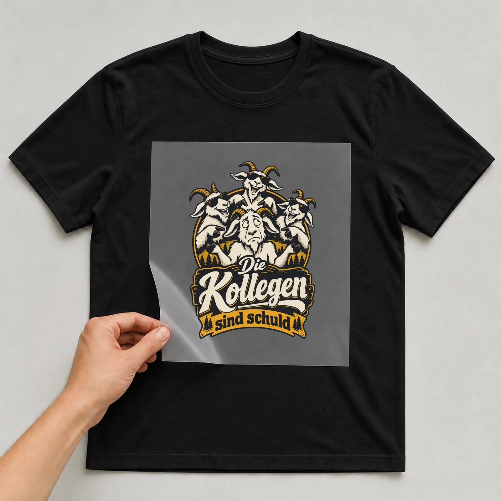Bügelbild Die Kollegen sind schuld auf schwarzem T-Shirt, Folie wird aufgelegt