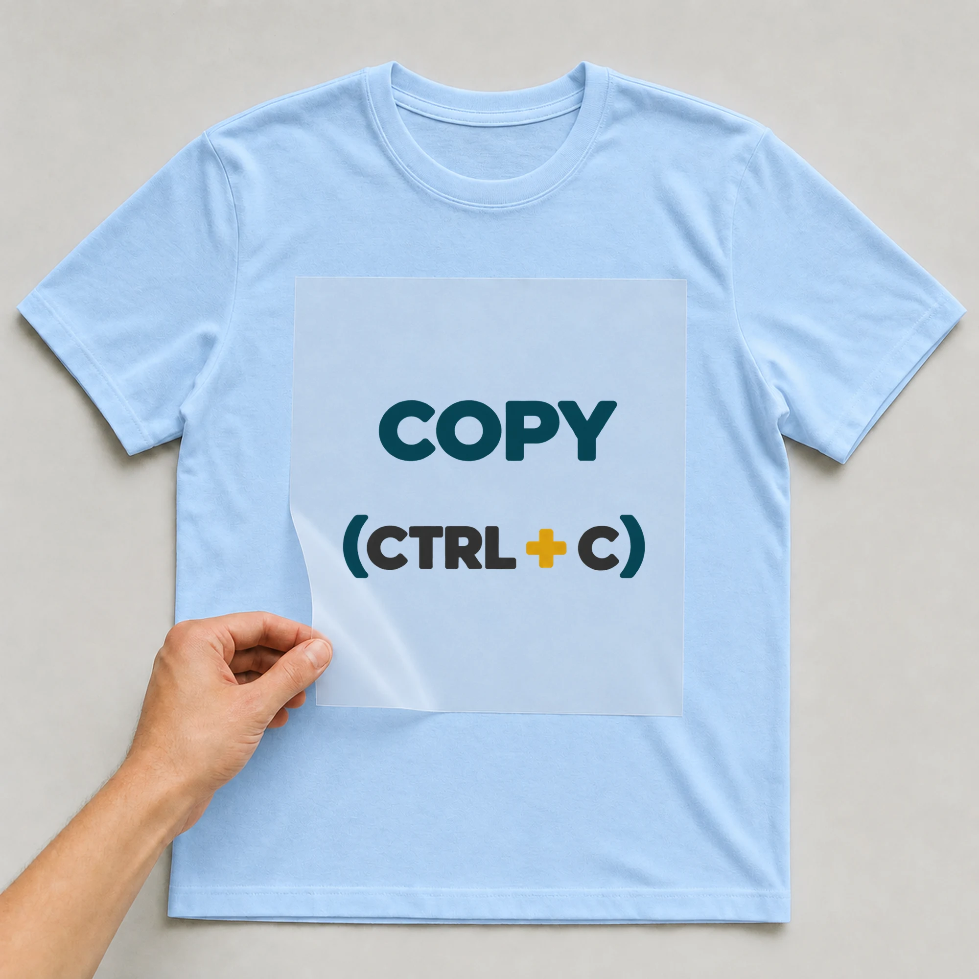 Bügelbild „COPY (CTRL + C)“ auf babyblauem T-Shirt, Folie wird aufgelegt