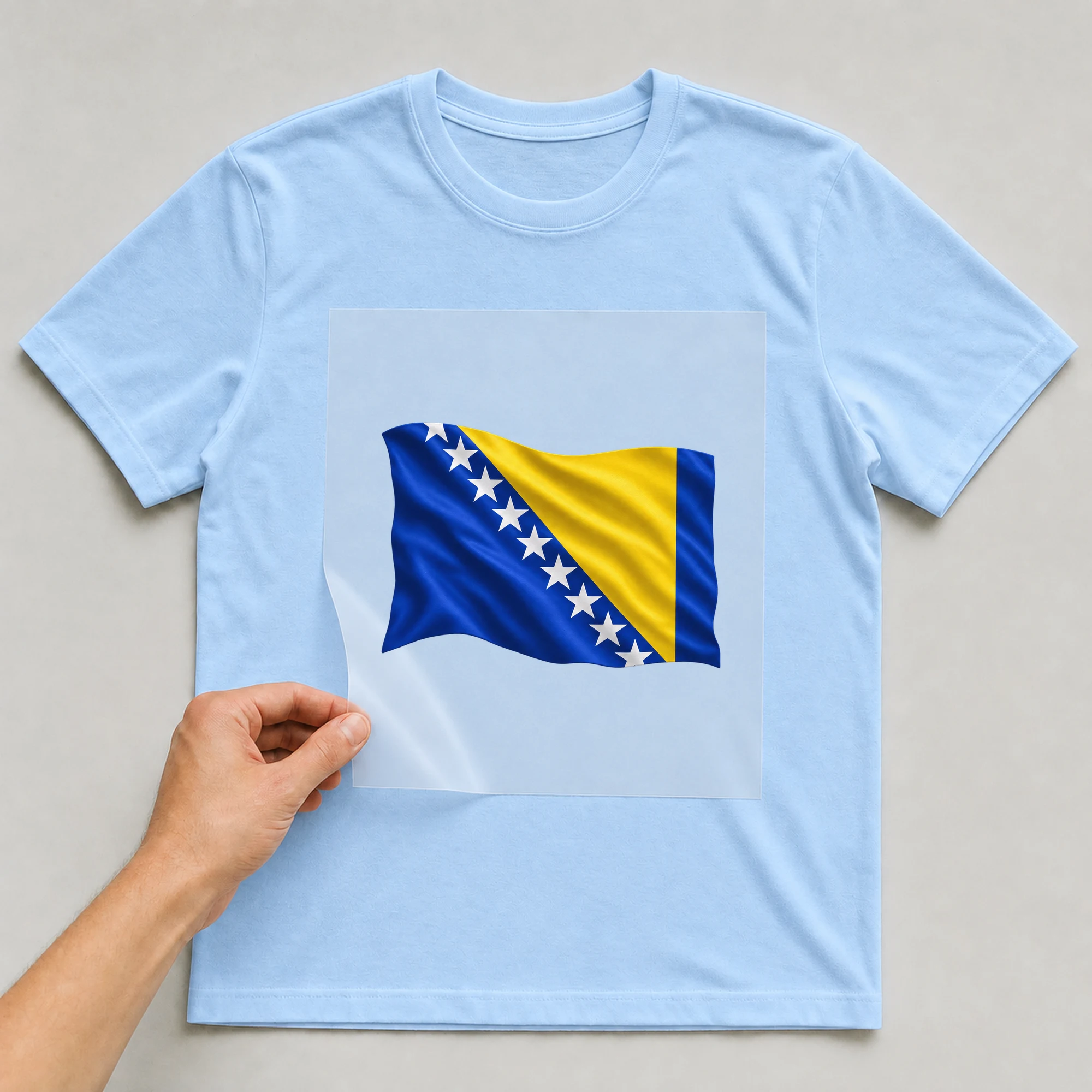 Bügelbild „BB021103-motiv-r03380“ auf babyblauem T-Shirt, Folie wird aufgelegt