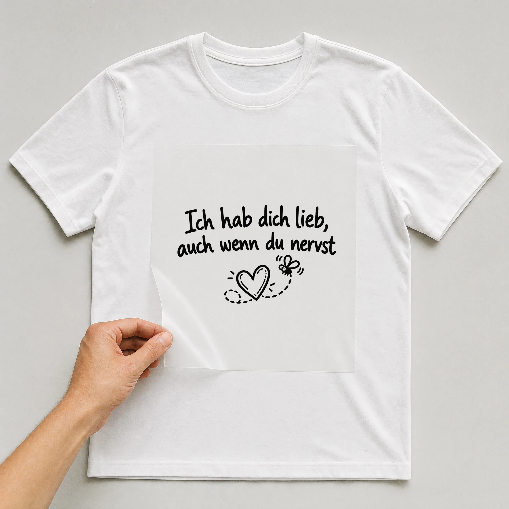 Bügelbild „Ich hab dich lieb, auch wenn du nervst“ auf weißem T-Shirt, Folie wird aufgelegt