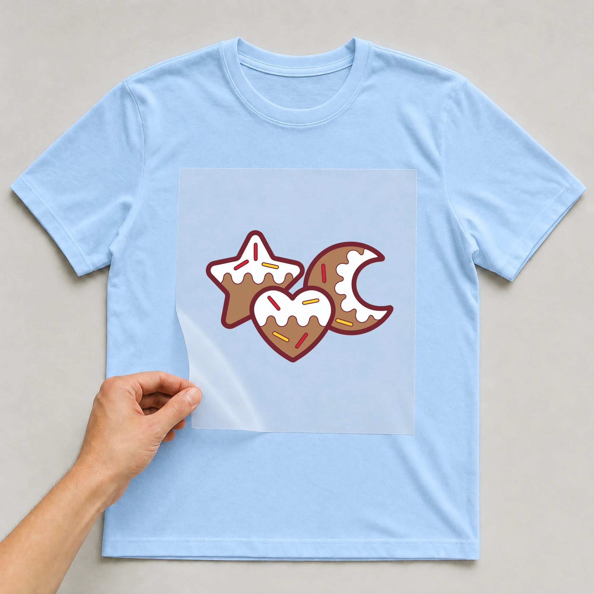 Bügelbild „Plätzchen“ auf babyblauem T-Shirt, Folie wird aufgelegt