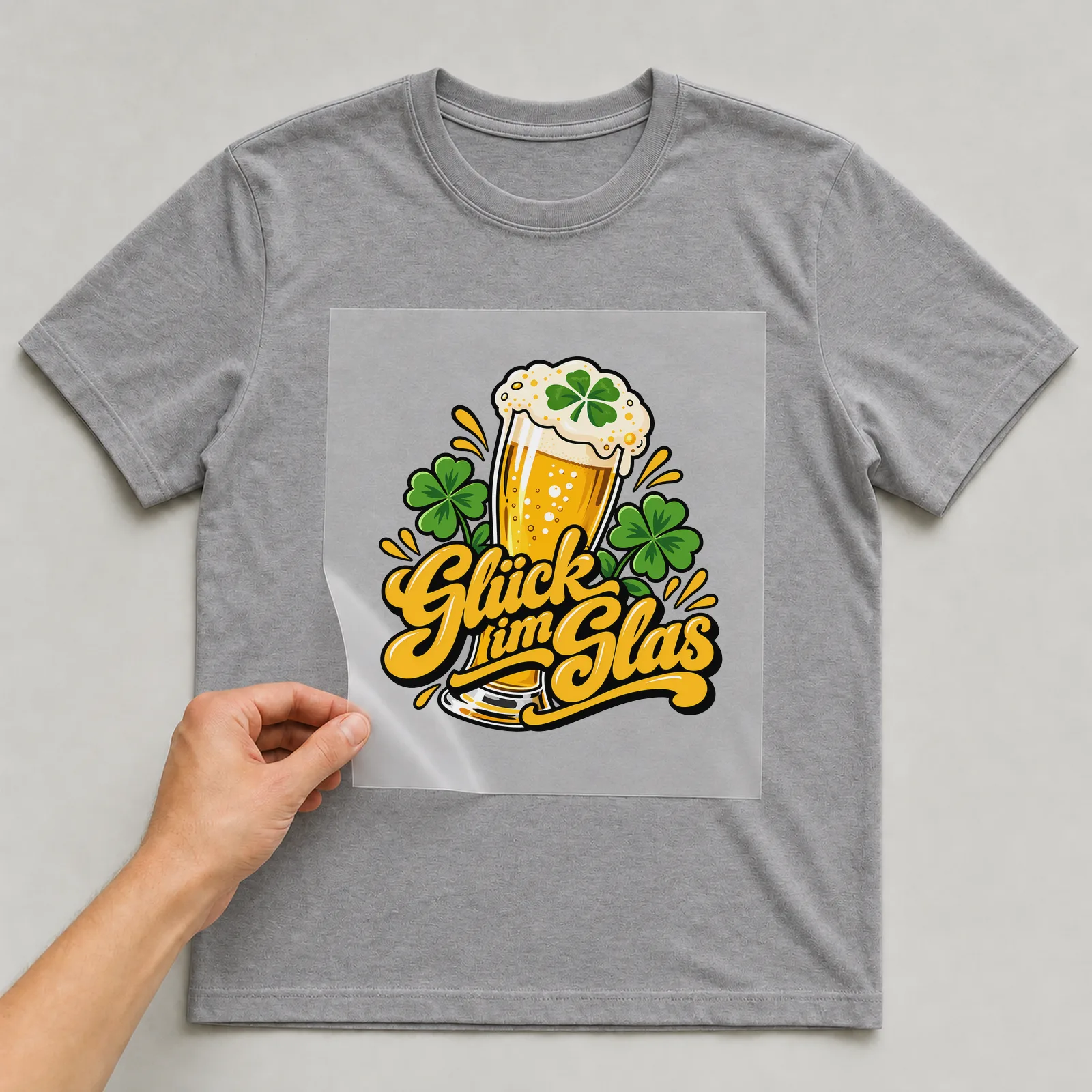 Bügelbild „Glück im Glas“ (organischen Formen) auf grauem T-Shirt, Folie wird aufgelegt