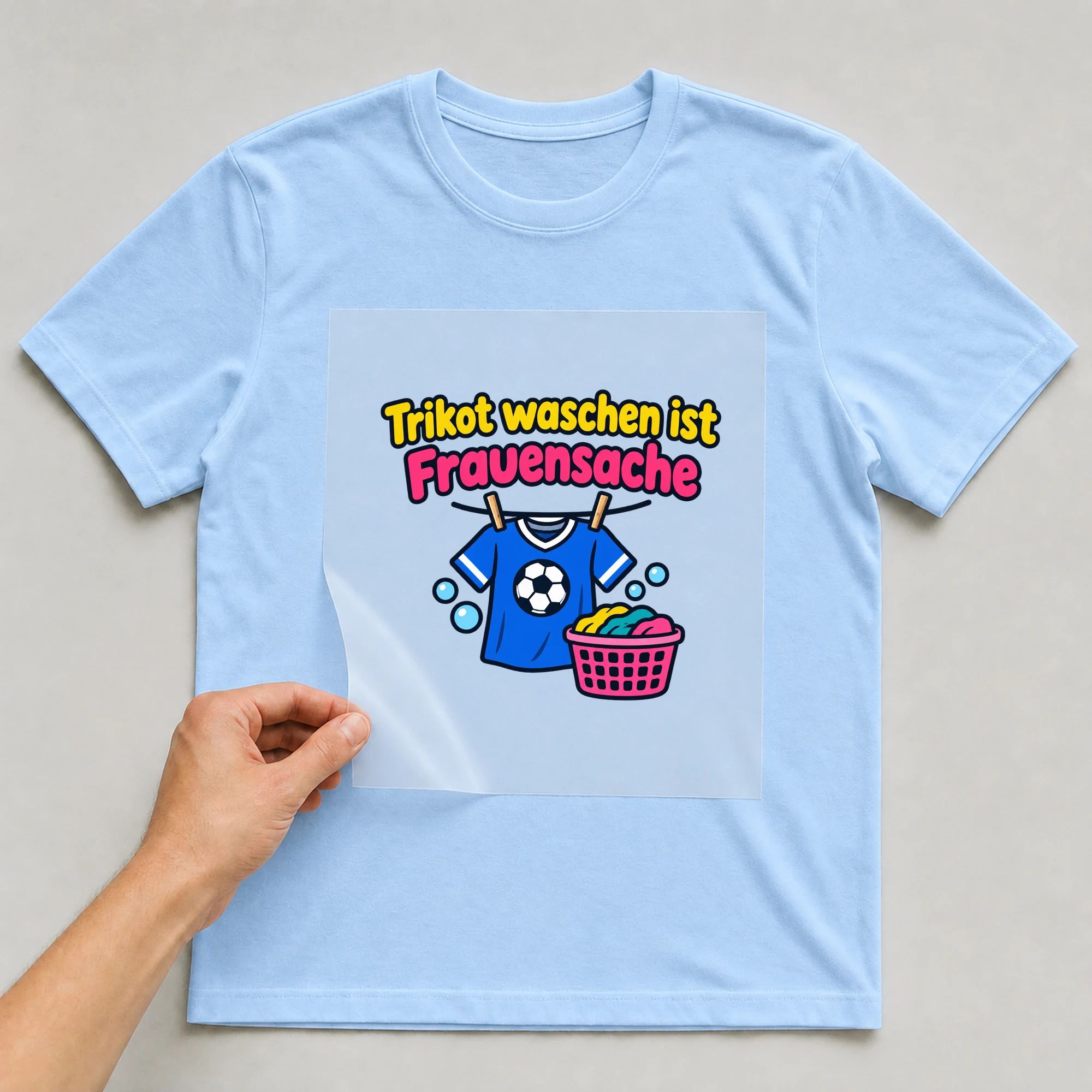 Bügelbild „Trikot waschen ist Frauensache“ auf babyblauem T-Shirt, Folie wird aufgelegt