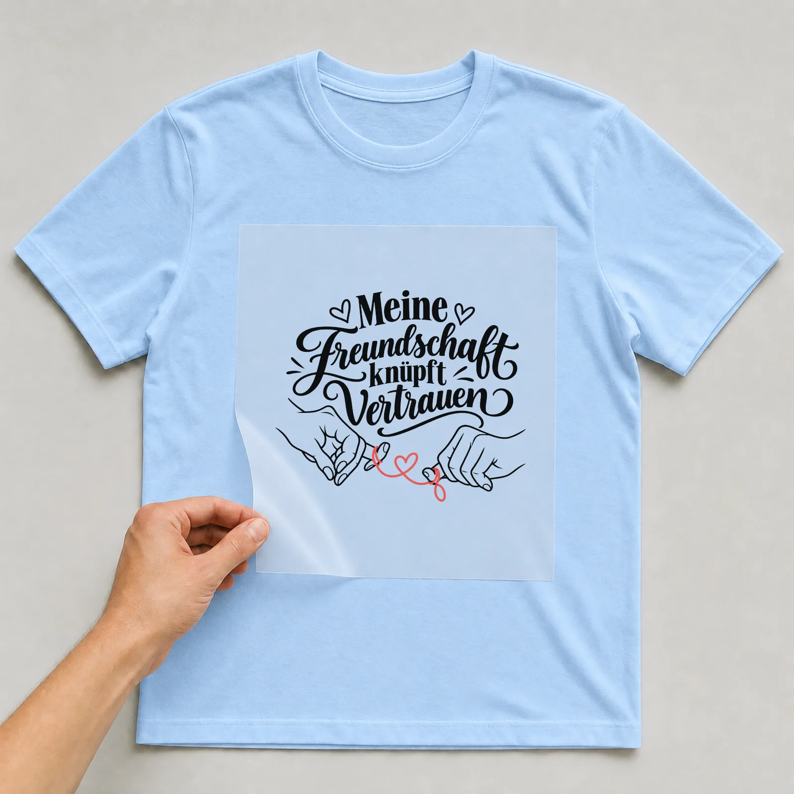 Bügelbild „Meine Freundschaft knüpft Vertrauen“ auf hellblauem T-Shirt, Folie wird aufgelegt