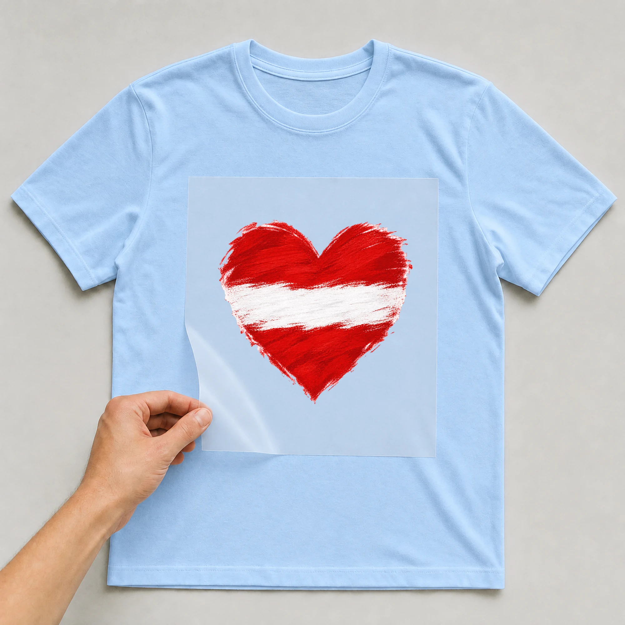 Bügelbild „Herz in Rot Weiß“ auf babyblauem T-Shirt, Folie wird aufgelegt