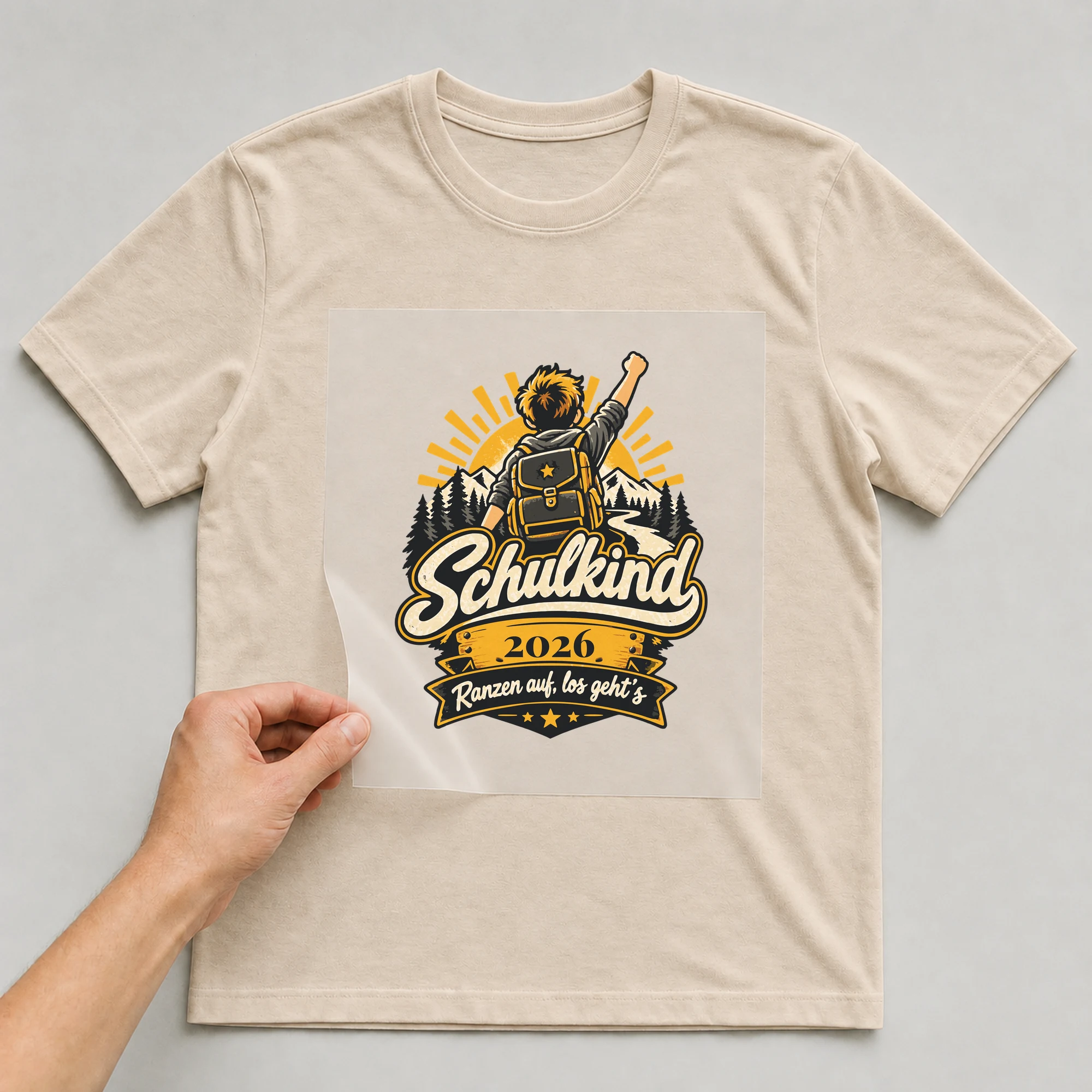 Bügelbild Schulkind: Ranzen auf, los geht’s mit Jahr auf beigem T-Shirt, Folie wird aufgelegt