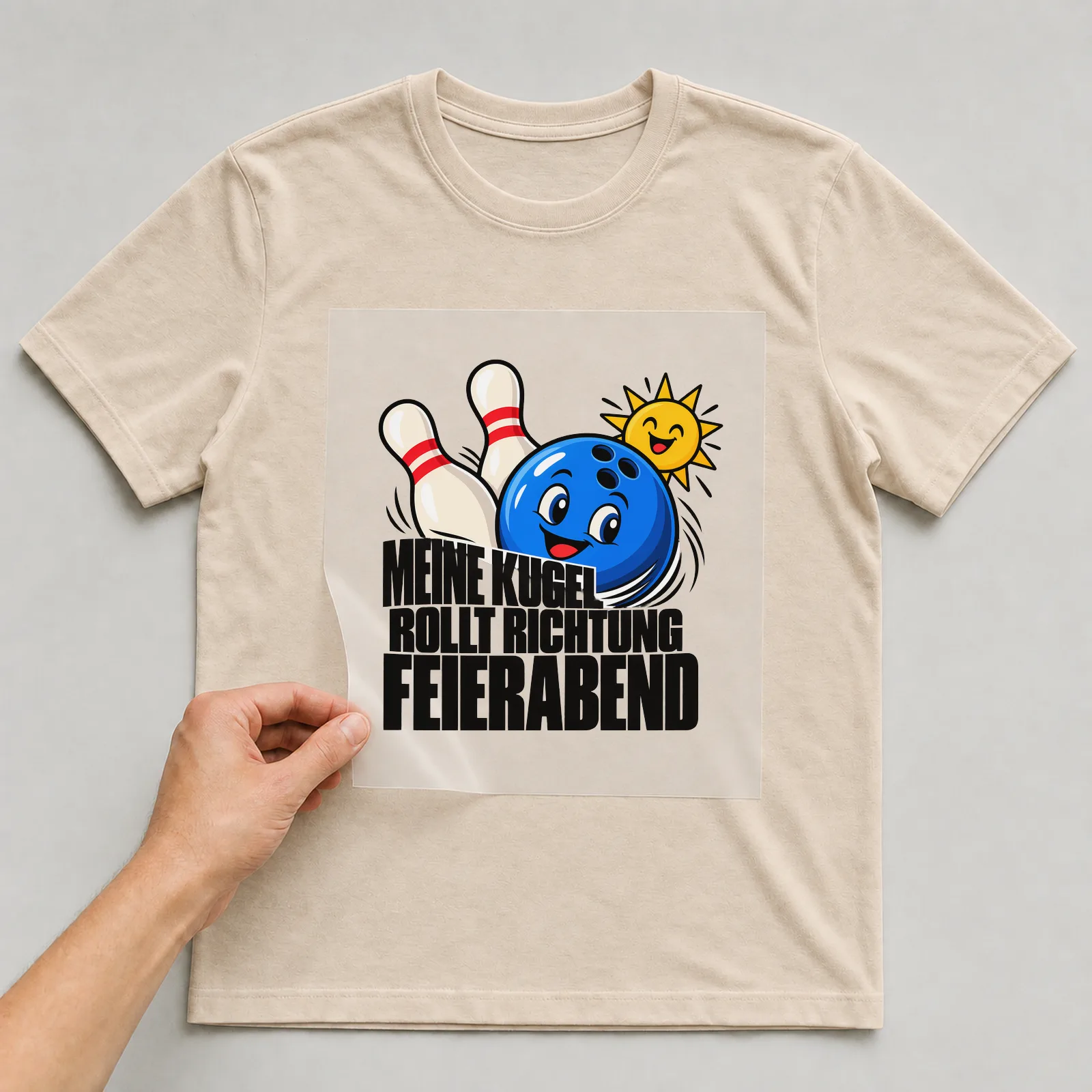 Bügelbild „Meine Kugel rollt Richtung Feierabend“ auf beigem T-Shirt, Folie wird aufgelegt