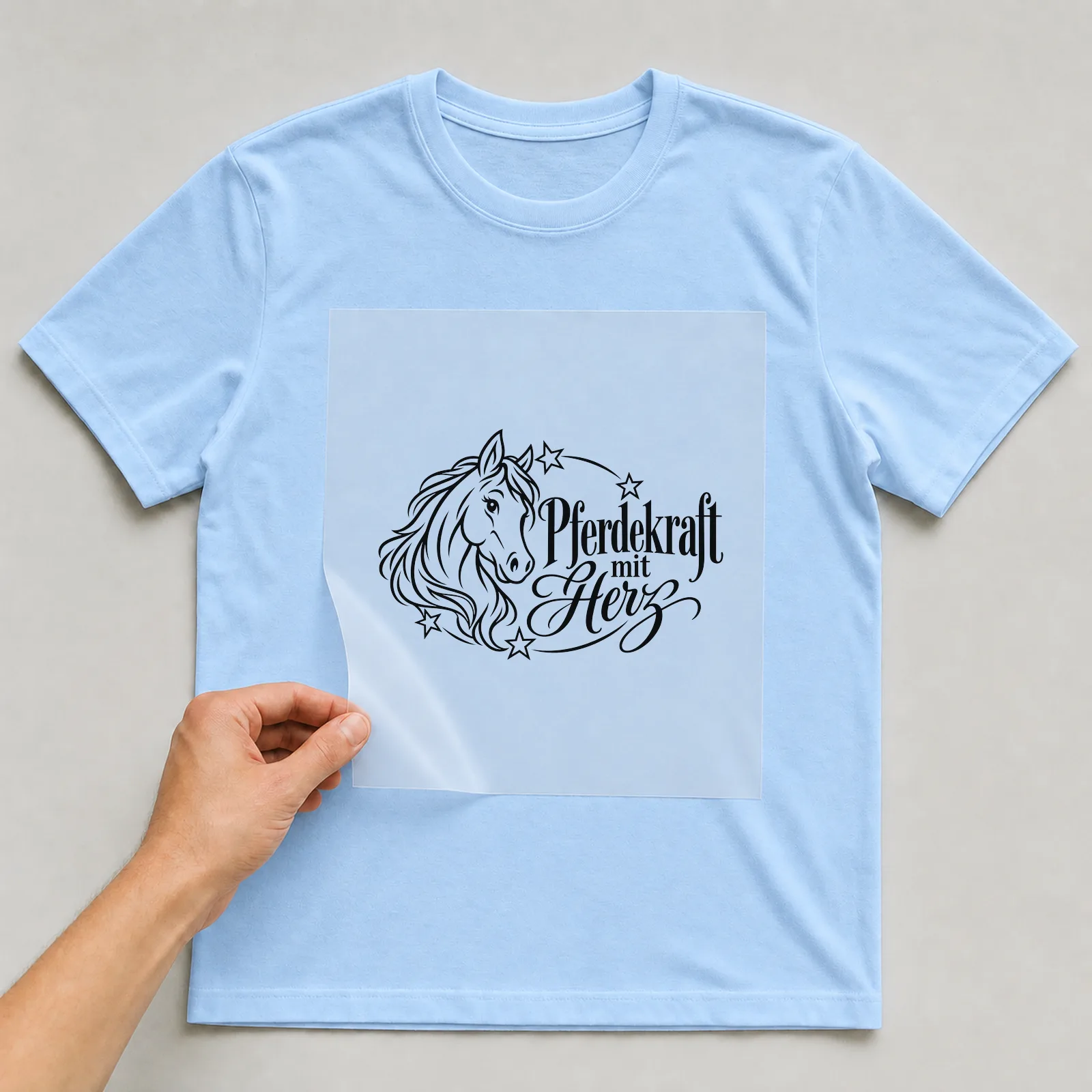 Bügelbild „Pferdekraft mit Herz“ auf hellblauem T-Shirt, Folie wird aufgelegt