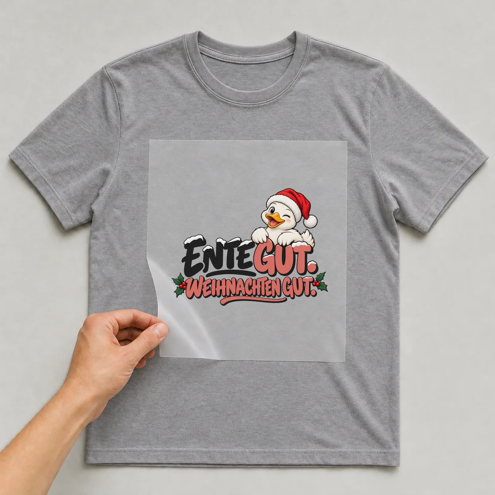 Bügelbild „Ente gut. Weihnachten gut.“ auf grauem T-Shirt, Folie wird aufgelegt