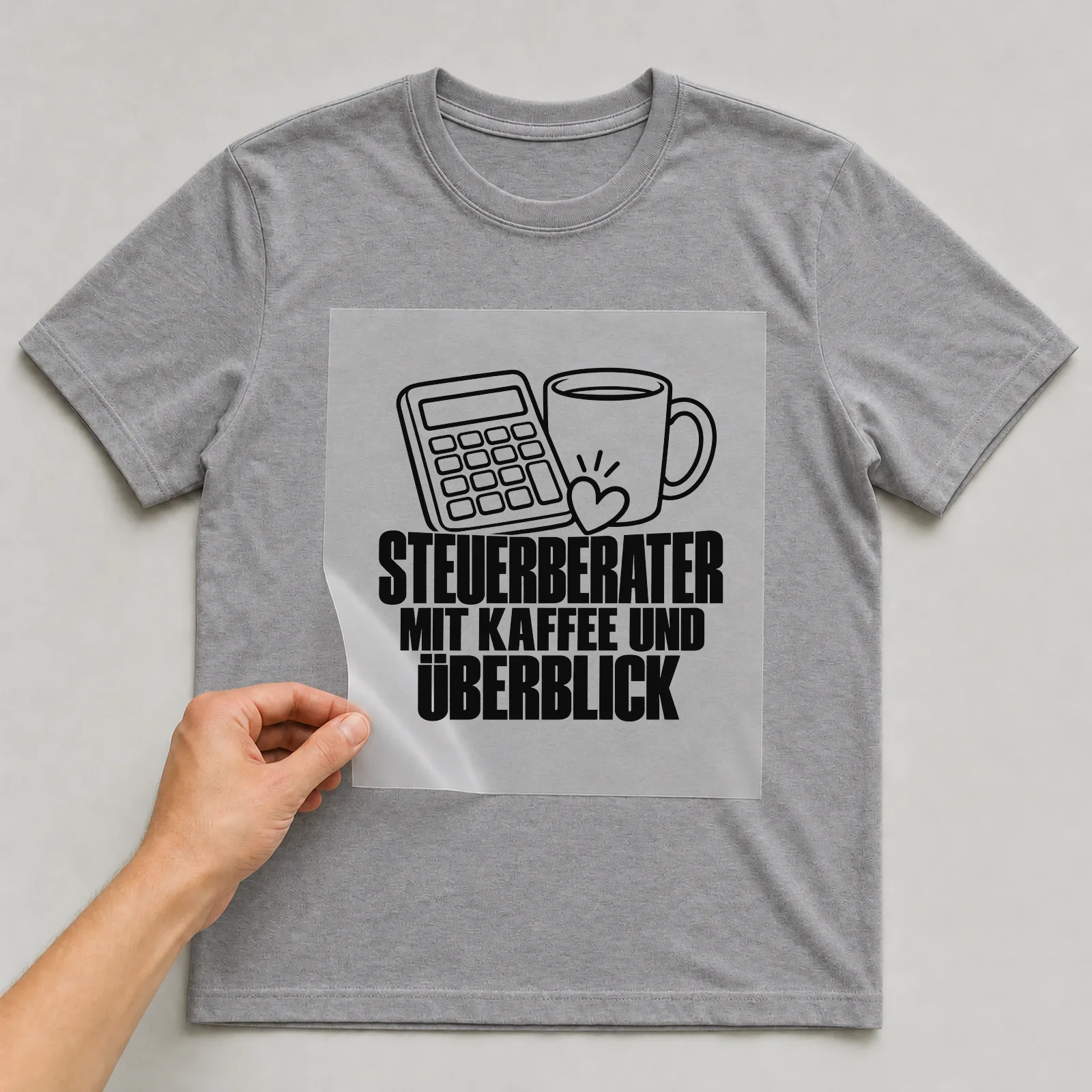 Bügelbild „Steuerberater mit Kaffee und Überblick“ auf grauem T-Shirt, Folie wird aufgelegt
