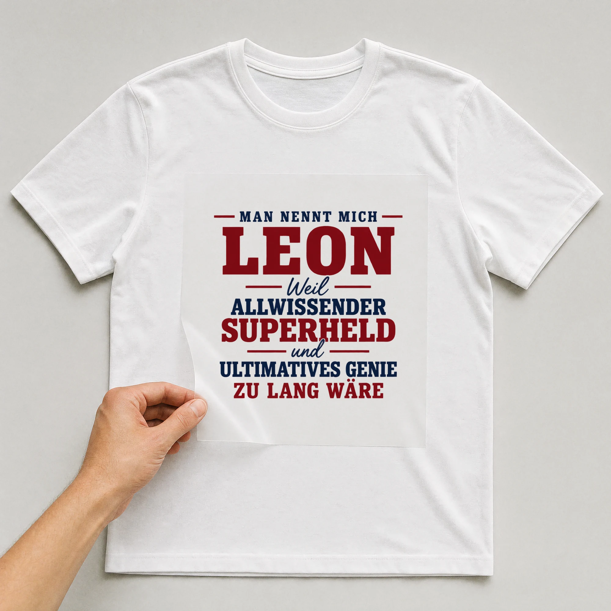 Bügelbild „Man nennt mich Leon weil allwissender Superheld und ultimatives Genie zu lang“ auf weißem T-Shirt, Folie wird aufgelegt