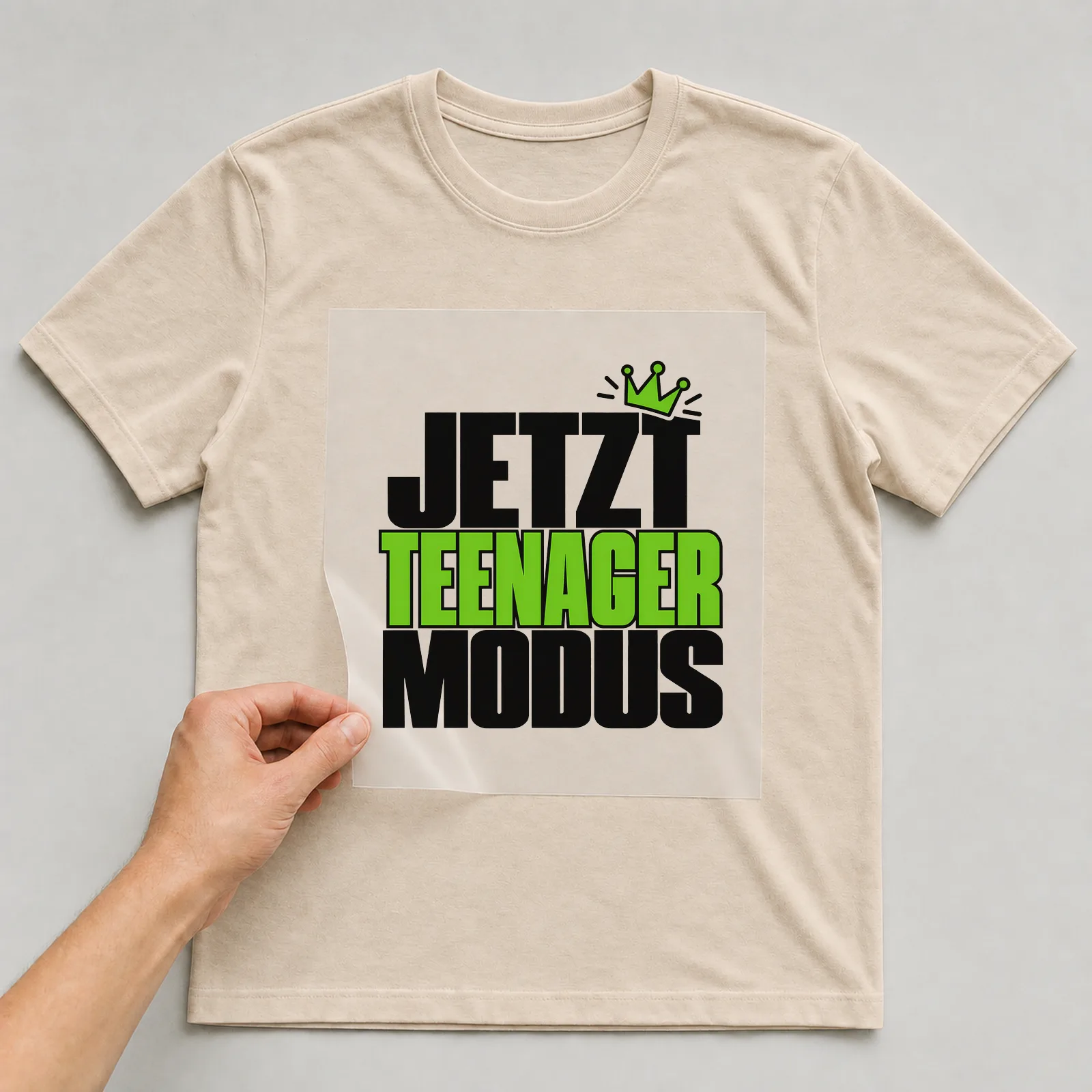 Bügelbild „Jetzt Teenager Modus“ auf beigem T-Shirt, Folie wird aufgelegt