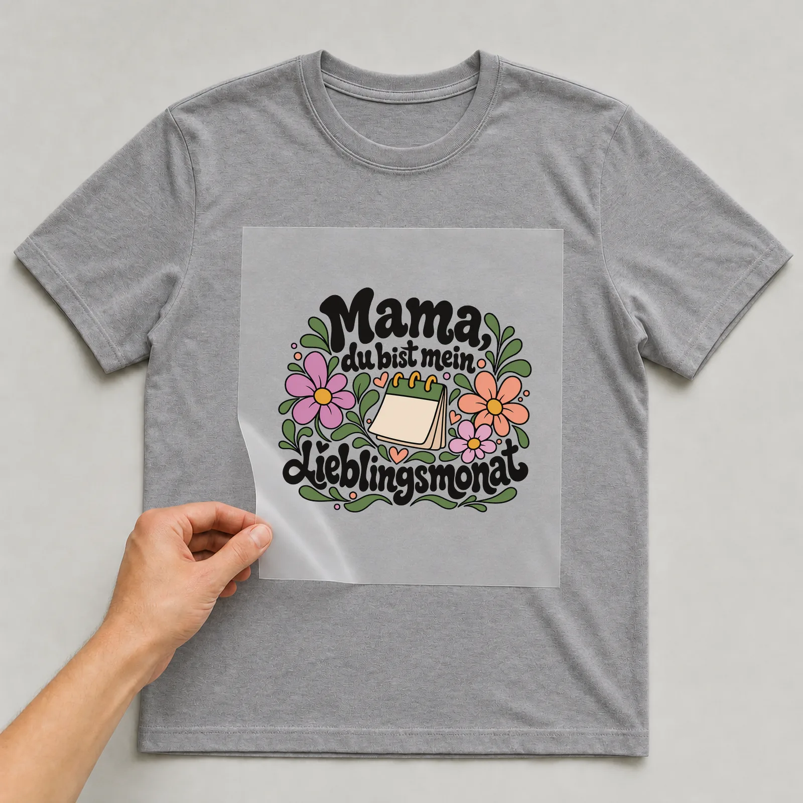 Bügelbild „Mama, du bist mein Lieblingsmonat“ auf grauem T-Shirt, Folie wird aufgelegt