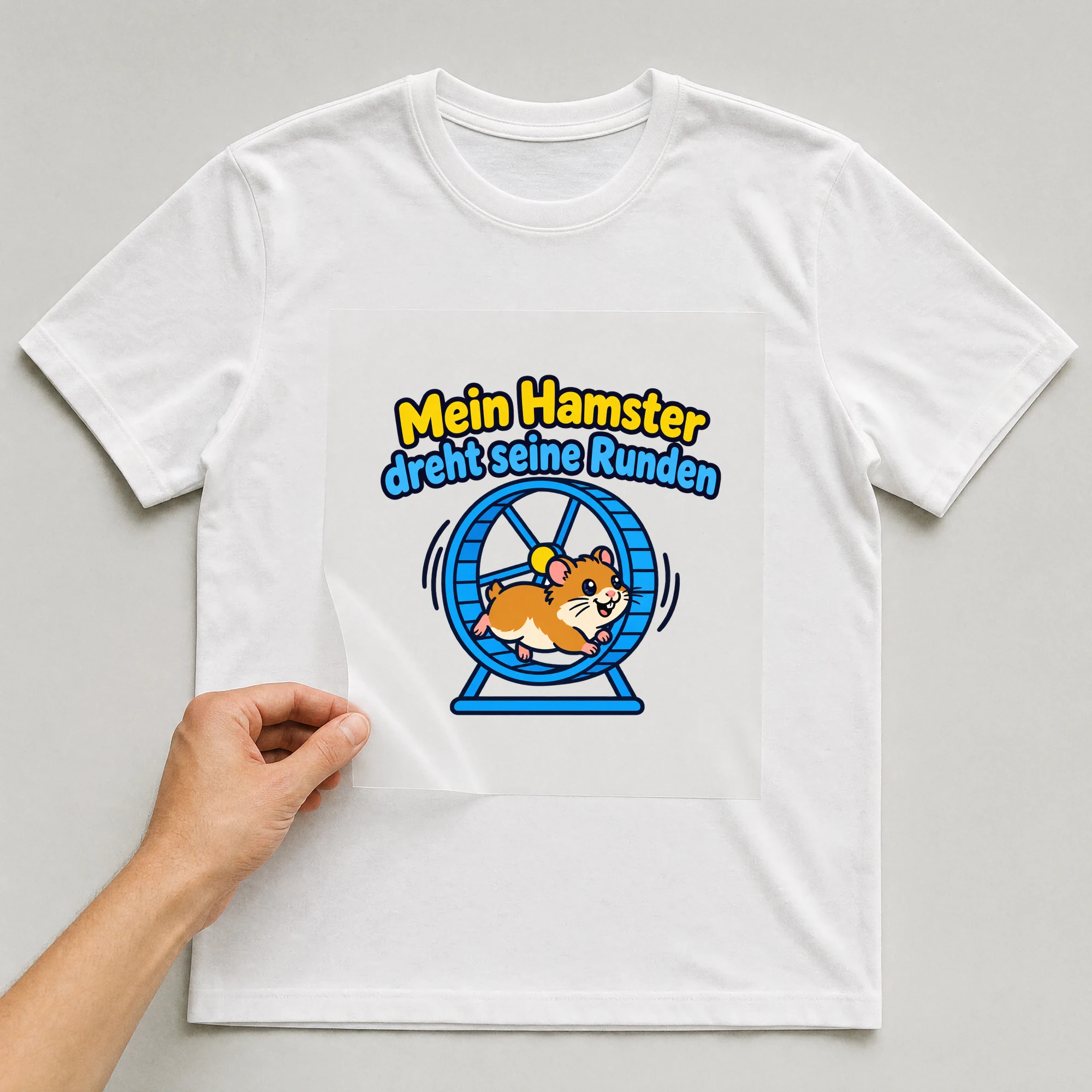 Bügelbild „Mein Hamster dreht seine Runden“ auf weißem T-Shirt, Folie wird aufgelegt
