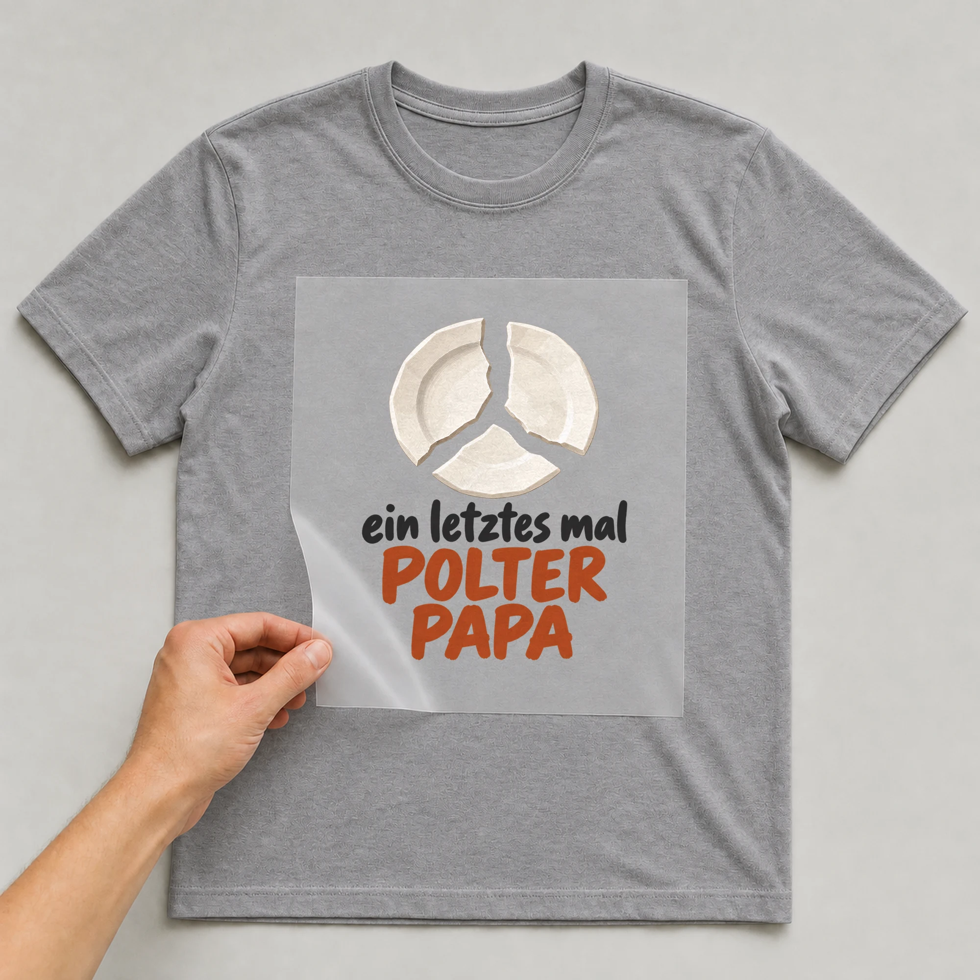 Bügelbild „Ein letztes Mal Polter Papa“ auf grauem T-Shirt, Folie wird aufgelegt
