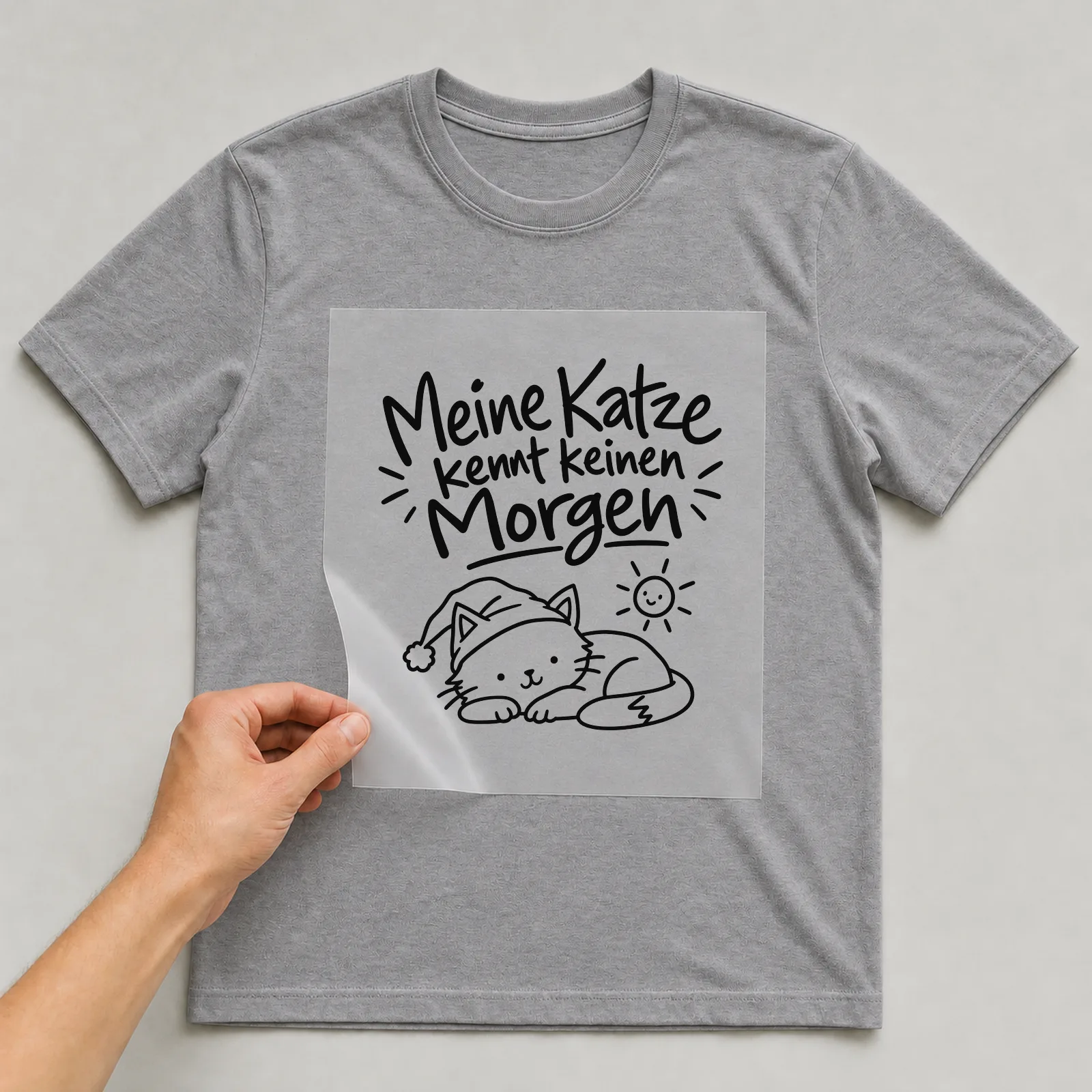 Bügelbild „Meine Katze kennt keinen Morgen“ auf grauem T-Shirt, Folie wird aufgelegt