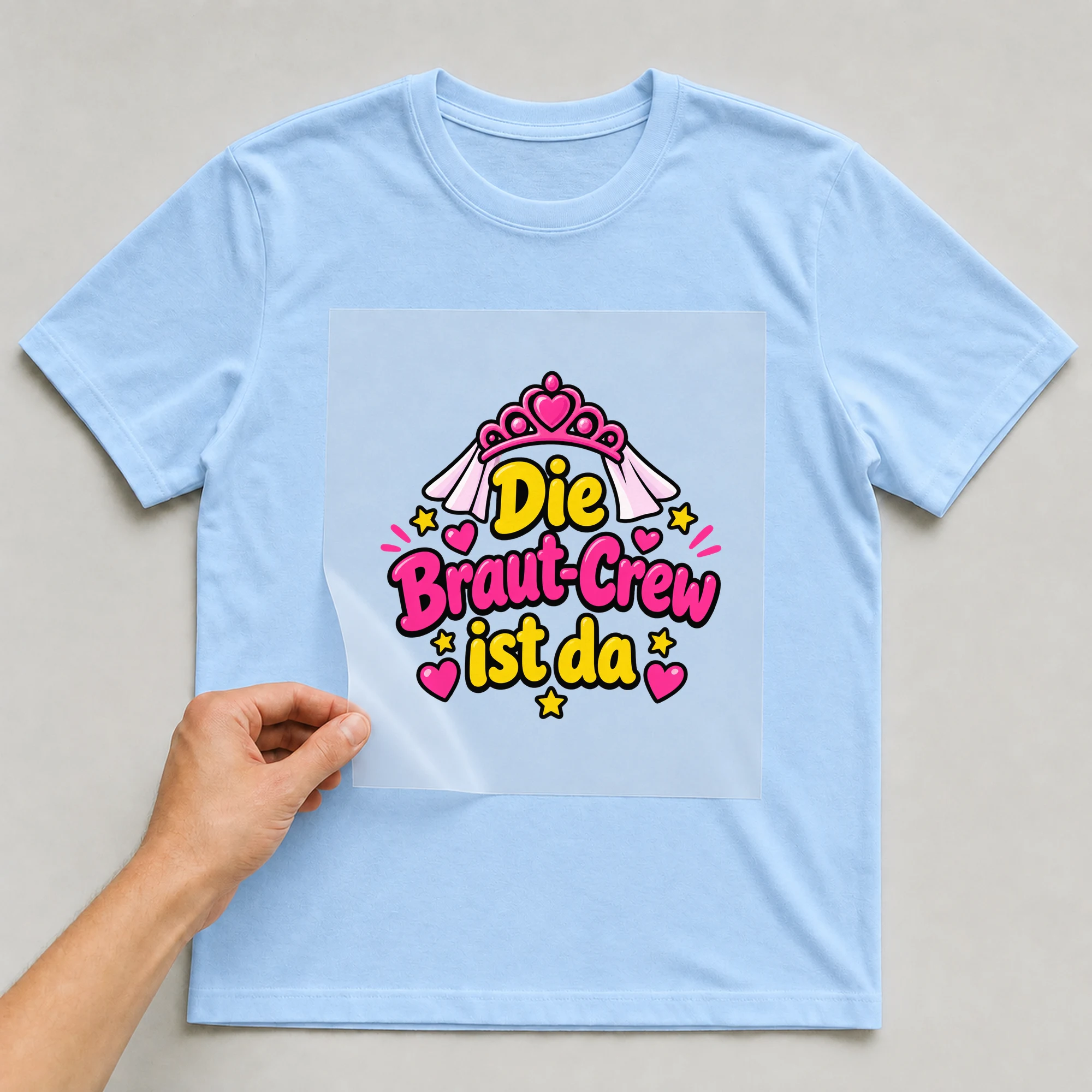 Bügelbild „Die braut crew ist da“ auf babyblauem T-Shirt, Folie wird aufgelegt