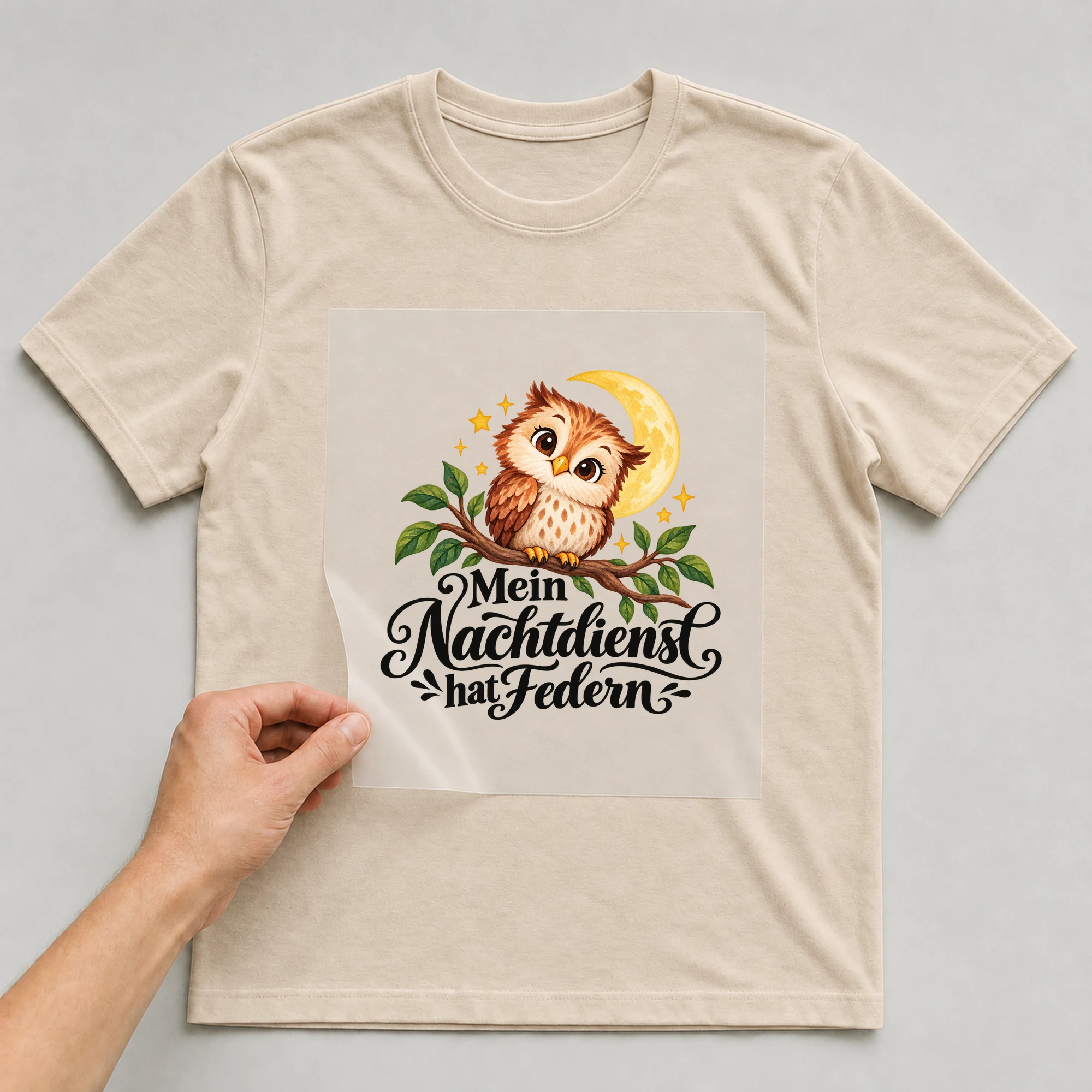Bügelbild „Mein Nachtdienst hat Federn“ auf beigem T-Shirt, Folie wird aufgelegt