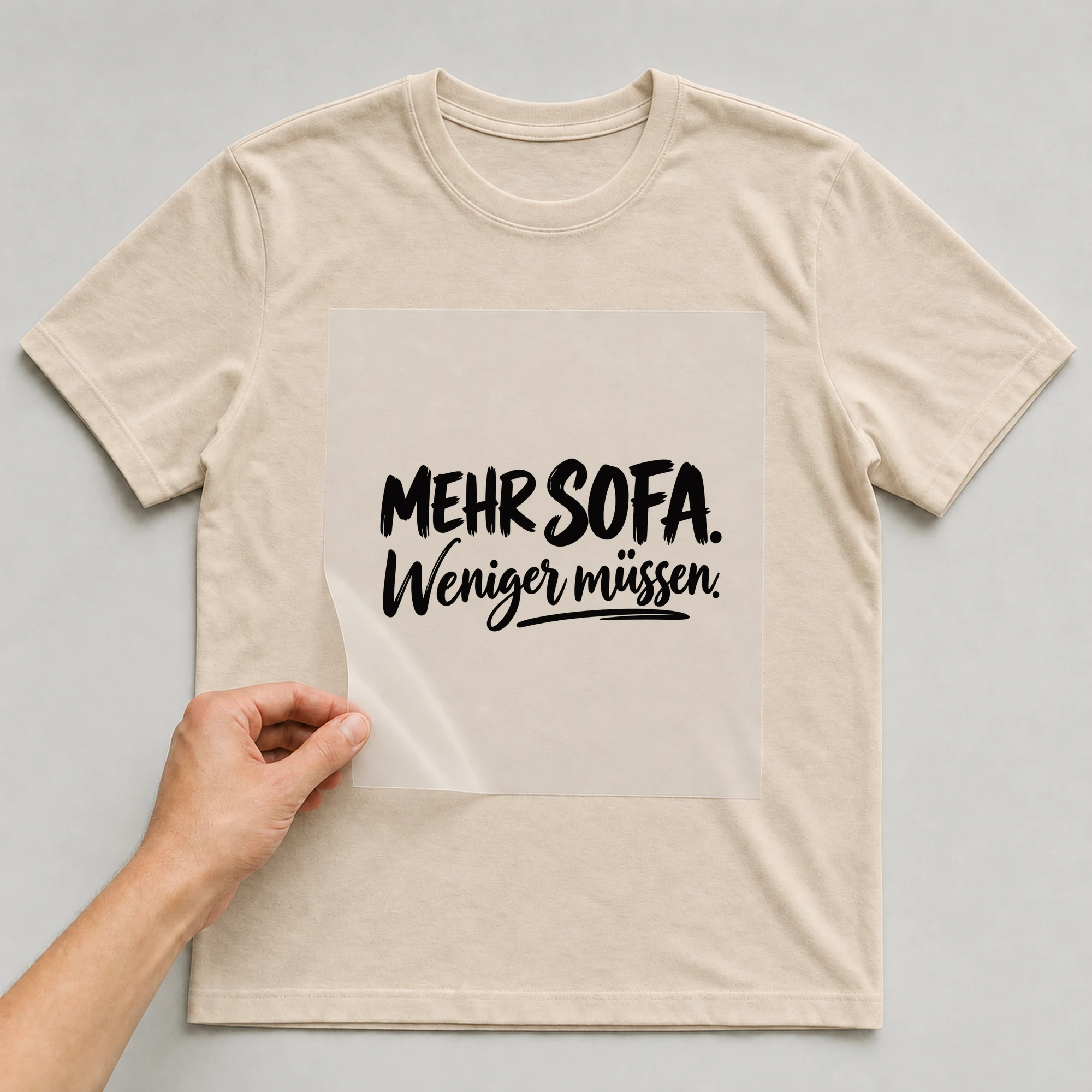 Bügelbild „Mehr Sofa. Weniger müssen.“ auf babyblauem T-Shirt, Folie wird aufgelegt