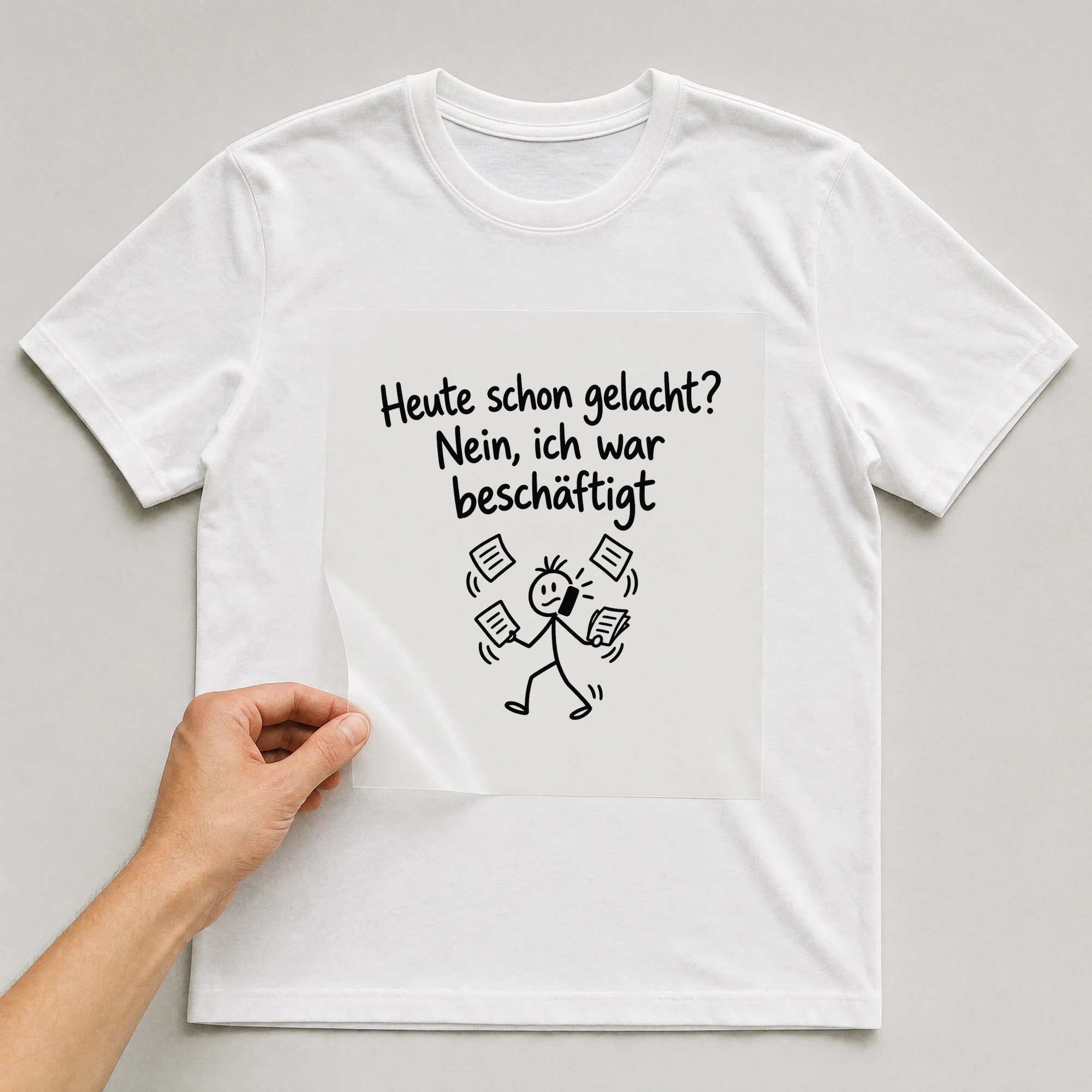 Bügelbild „Heute schon gelacht? Nein, ich war beschäftigt“ auf weißem T-Shirt, Folie wird aufgelegt