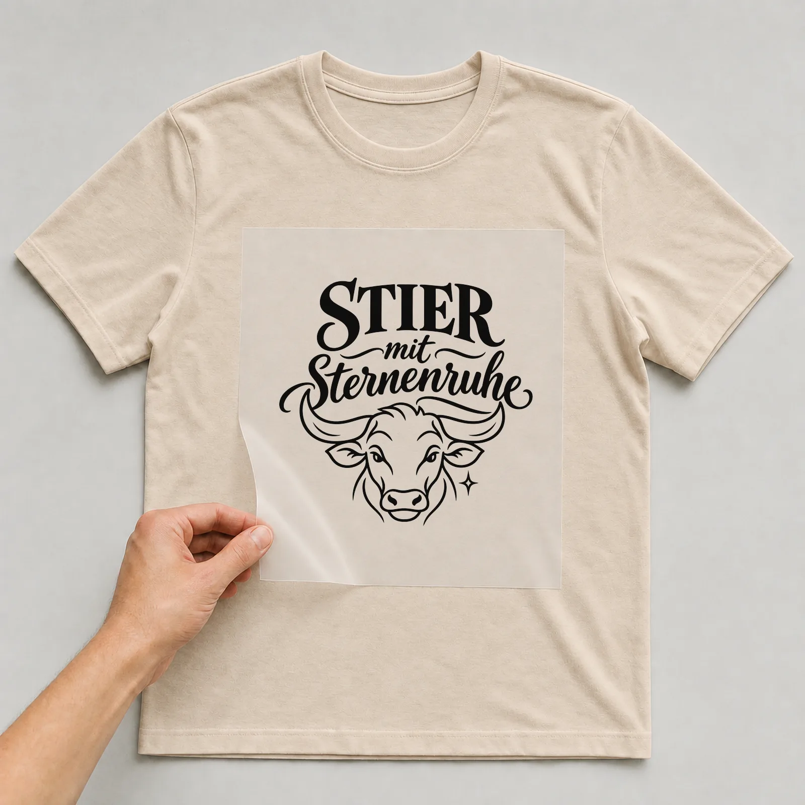 Bügelbild „Stier mit Sternenruhe“ auf beigem T-Shirt, Folie wird aufgelegt