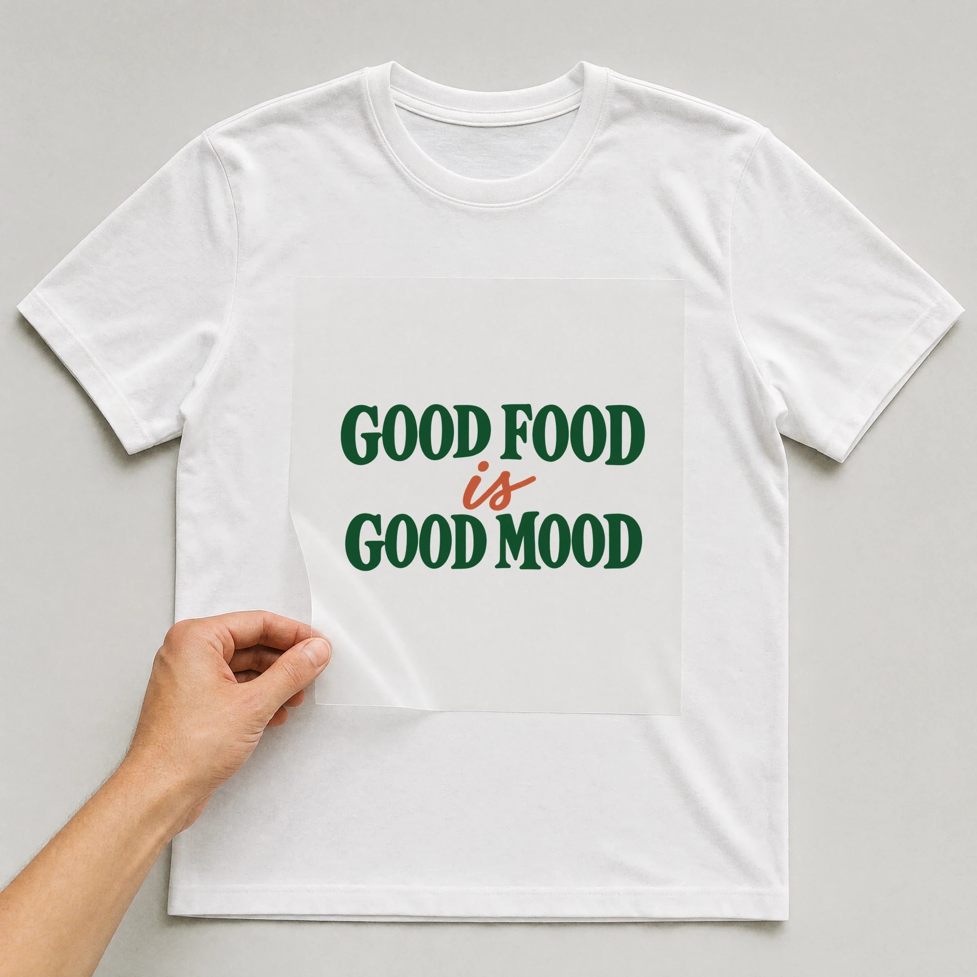 Bügelbild „Good Food Is Good Mood“ auf weißem T-Shirt, Folie wird aufgelegt
